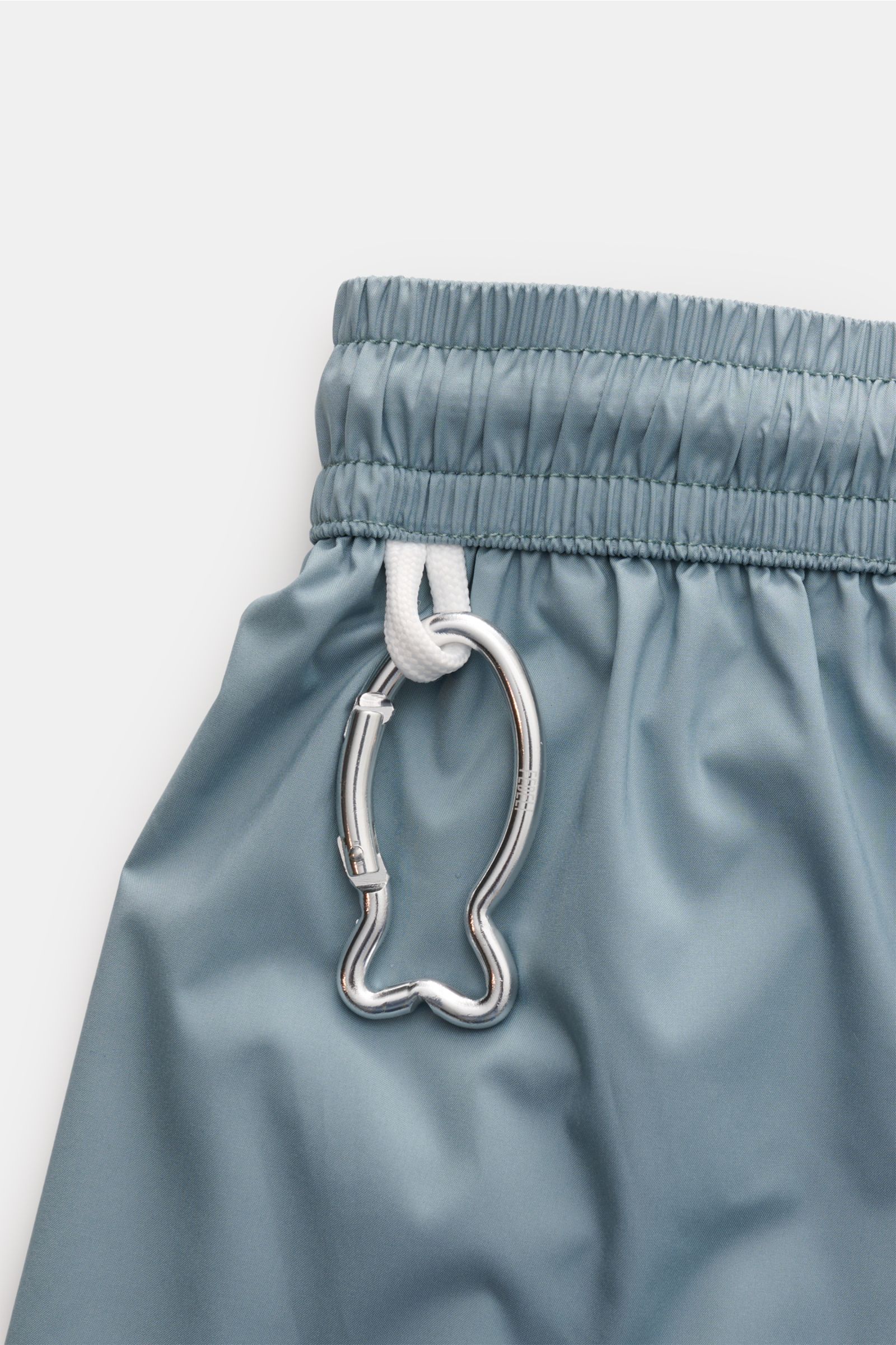 Fedeli Badeshorts 'Madeira Airstop' rauchblau, Detailaufnahme seitlich am elastischen Bund mit Karabinerhaken in Walform, schnelltrocknend, Regular Fit.