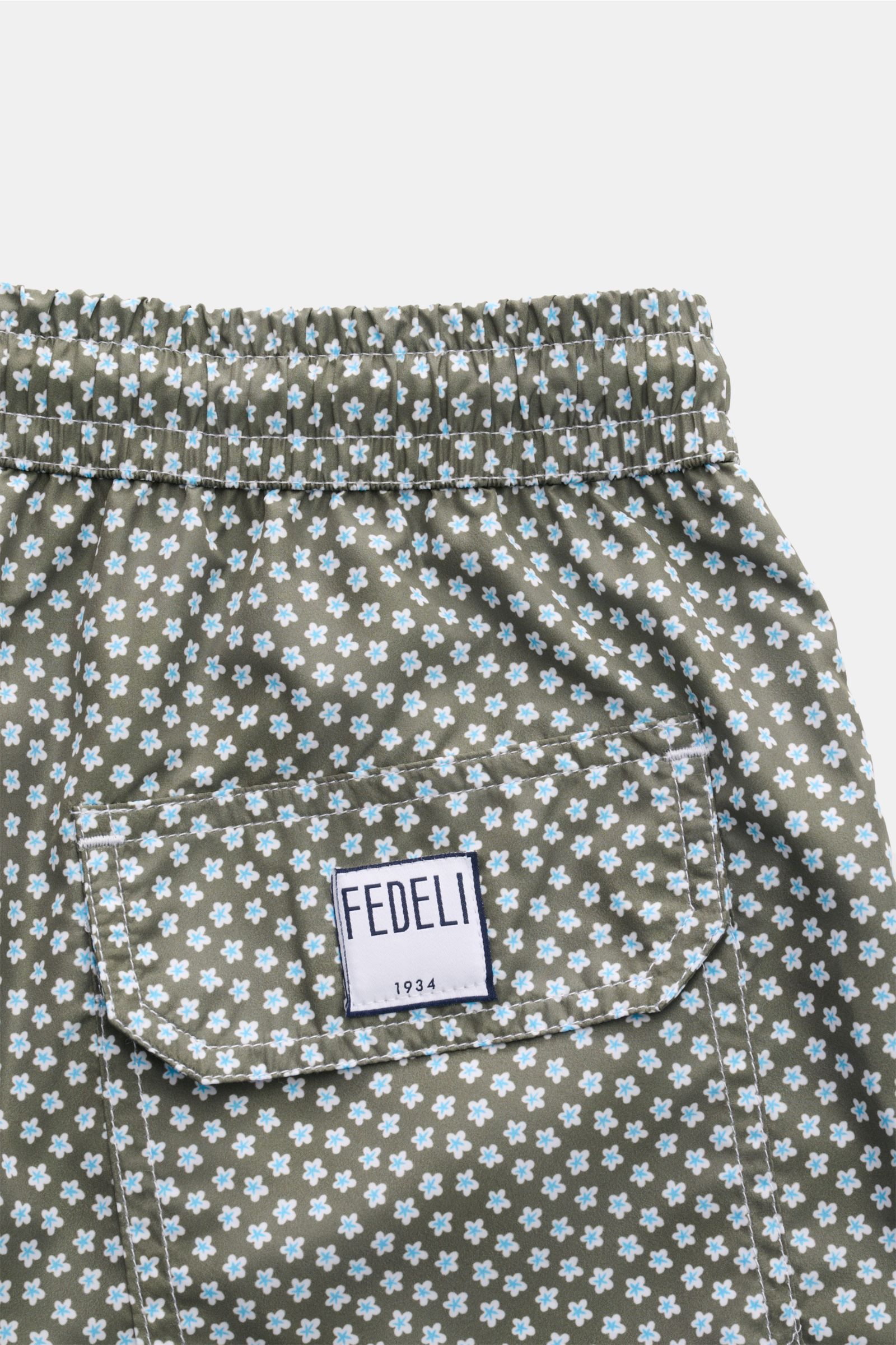 Close-up rear view of Fedeli Swim shorts 'Madeira Airstop' green/white/light blue patterned with floral print, elastic waistband, back pocket with FEDELI label.

Description: 
An essential for your summer vacation: These FEDELI swim shorts have an expr