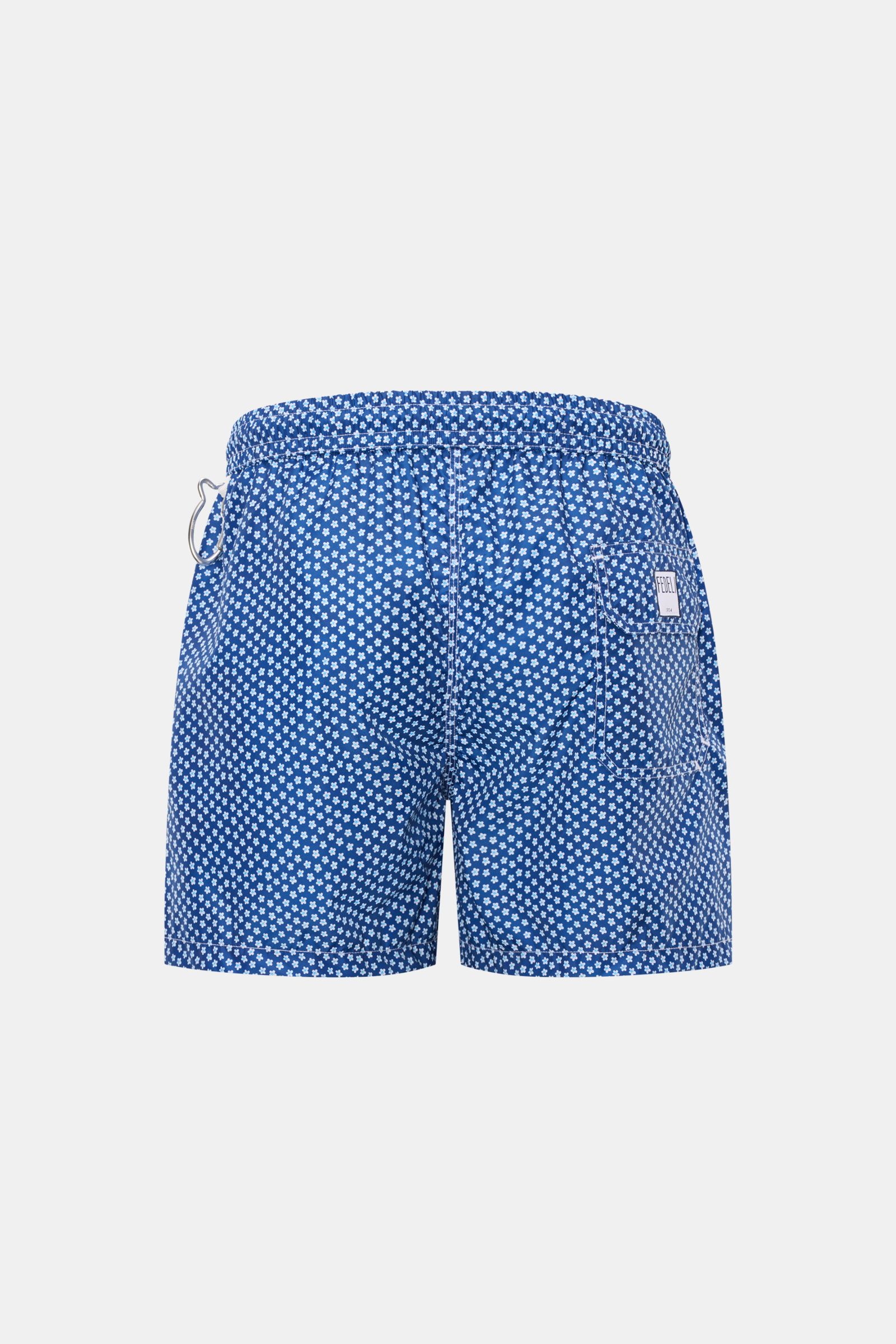 Rear view of Fedeli Swim shorts 'Madeira Airstop' blue/white/light blue patterned with elasticated waistband, back pocket, and whale-shaped carabiner.

An essential for your summer vacation: These FEDELI swim shorts have an expressive pattern that adds