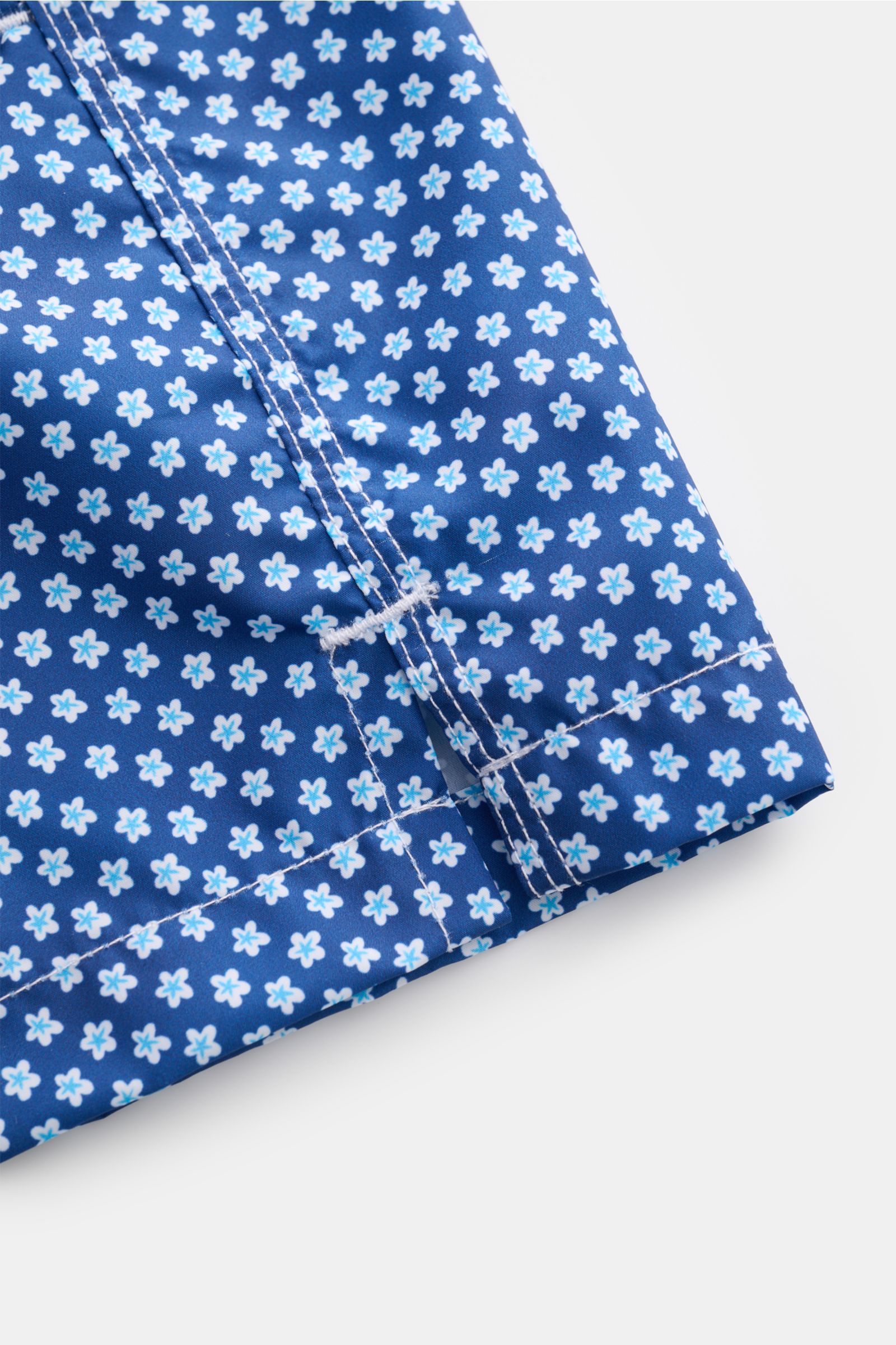 Close-up view of the hem and side vent of Fedeli Swim shorts 'Madeira Airstop' blue/white/light blue patterned with floral print.

An essential for your summer vacation: These FEDELI swim shorts have an expressive pattern that adds stylish accents and 