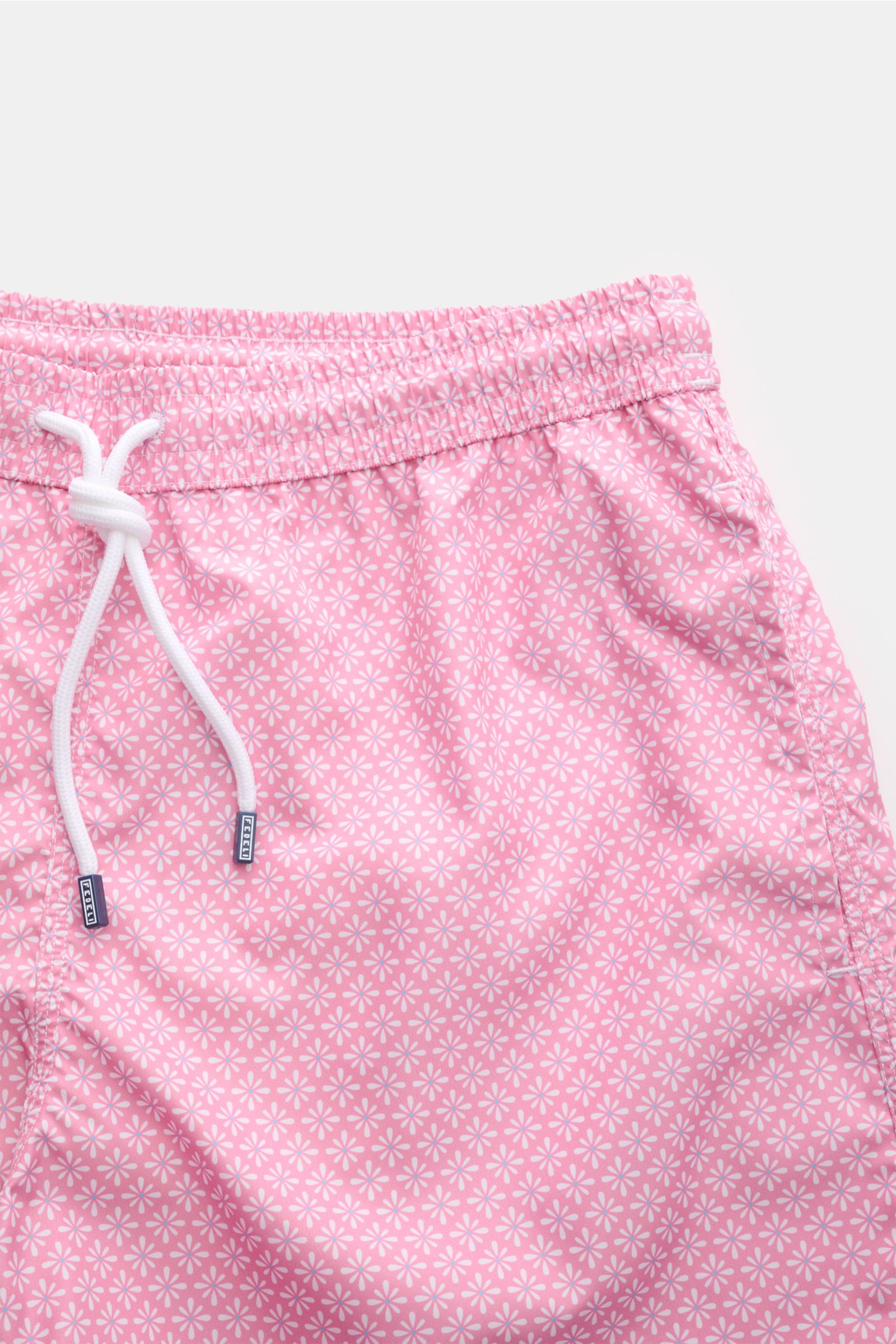 Close-up front view of Fedeli Swim shorts 'Madeira Airstop' rose/white patterned, featuring elastic waistband, white drawstring, and floral design.

An essential for your summer vacation: These FEDELI swim shorts have an expressive pattern that adds st