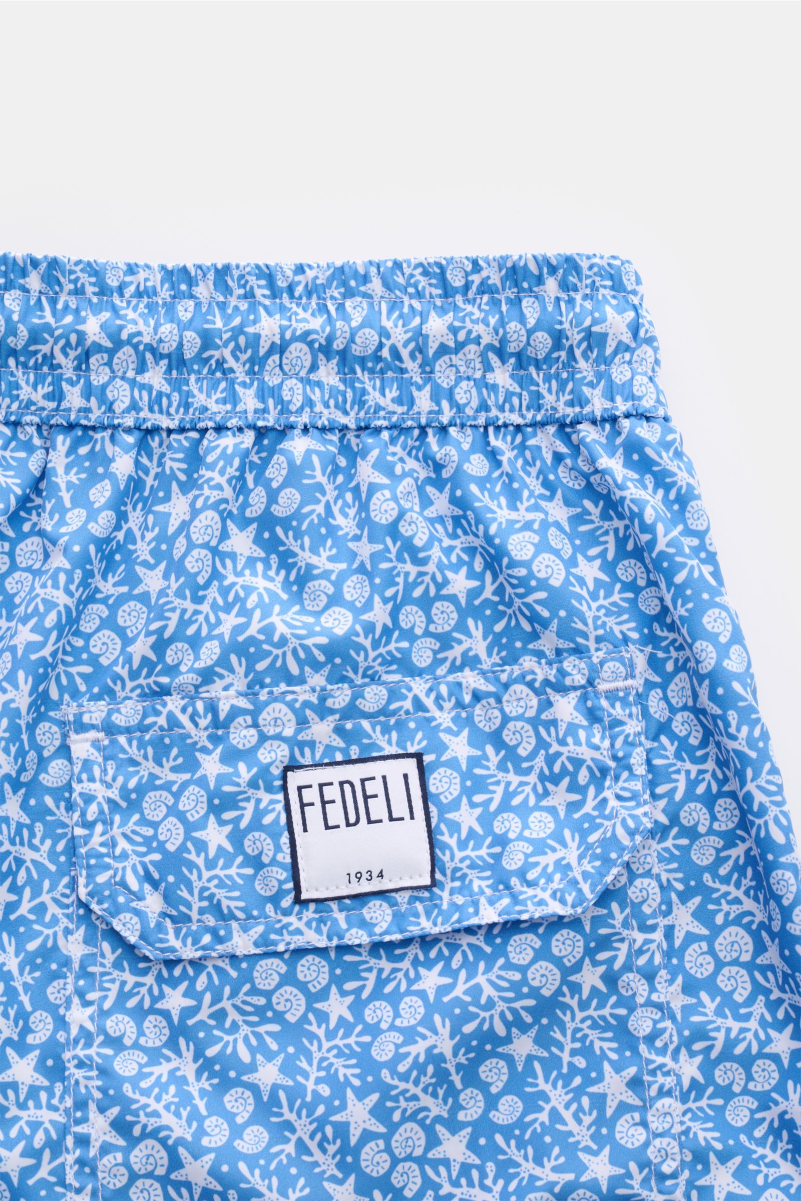 Close-up rear view of Fedeli Swim shorts 'Madeira Airstop' blue/white patterned with elasticated waistband and FEDELI label on back pocket.

An essential for your summer vacation: These FEDELI swim shorts have an expressive pattern that adds stylish ac