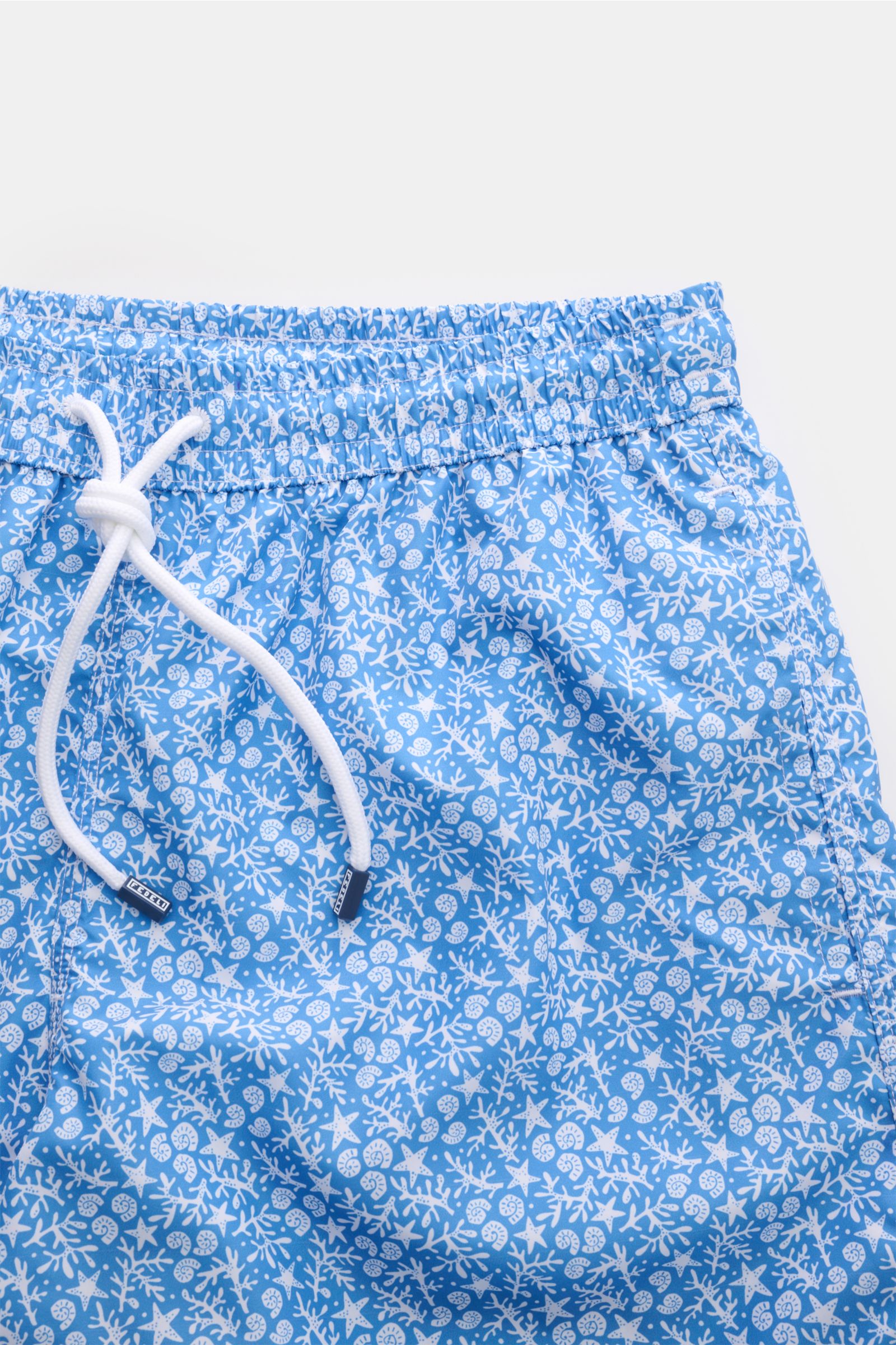 Close-up front view of Fedeli Swim shorts 'Madeira Airstop' blue/white patterned with elasticated waistband, white drawstring, and nautical pattern.

Description:
An essential for your summer vacation: These FEDELI swim shorts have an expressive patter