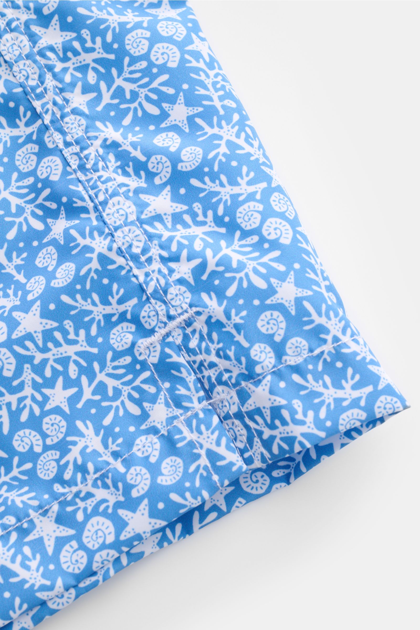 Close-up of the hem and side seam of Fedeli Swim shorts 'Madeira Airstop' blue/white patterned, showing the nautical design and stitching from a top angle.

An essential for your summer vacation: These FEDELI swim shorts have an expressive pattern that