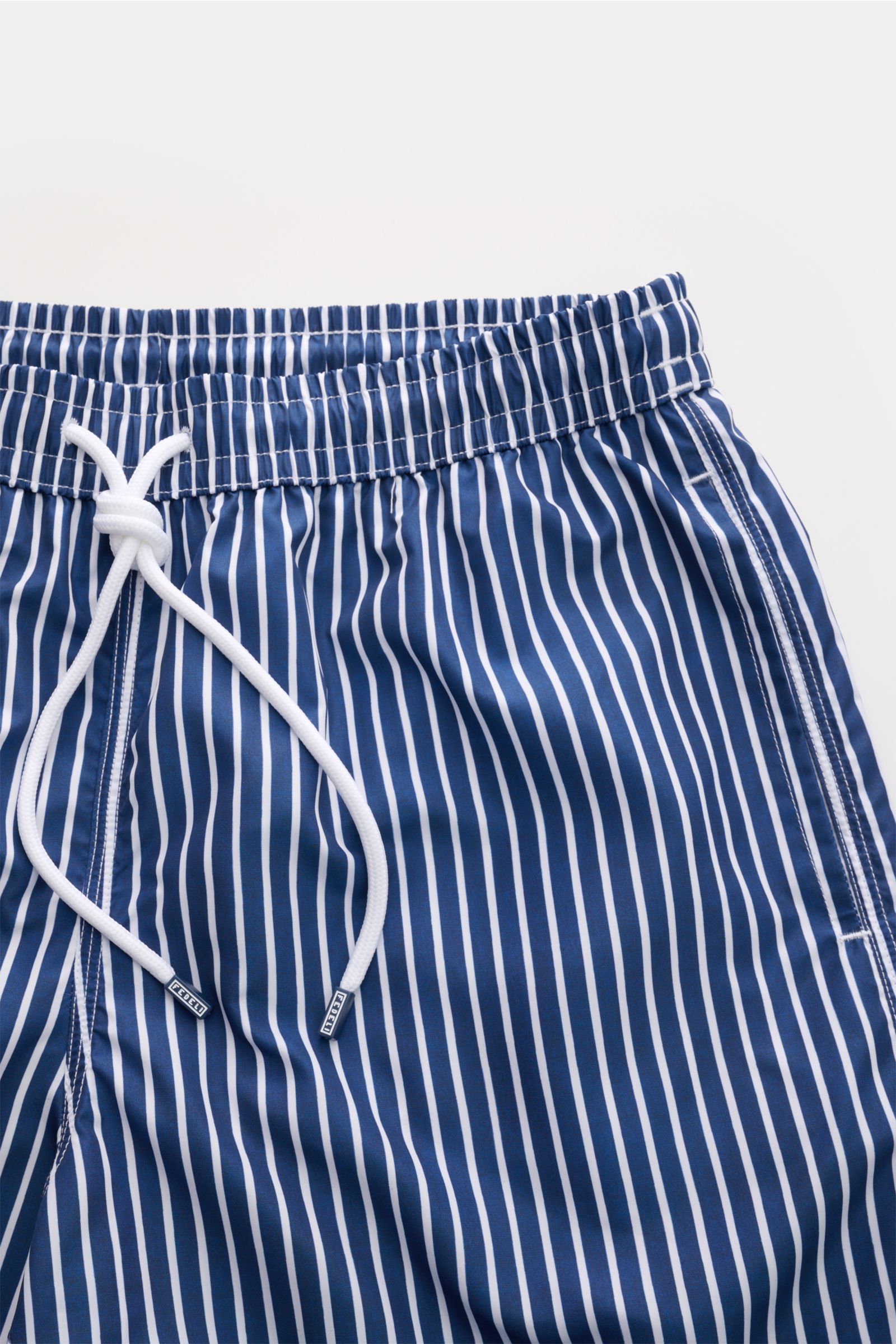 Fedeli Badeshorts 'Madeira Airstop' navy/weiß gestreift, schnelltrocknend, Regular Fit, elastischer Bund, seitliche Taschen, Nahaufnahme von oben.