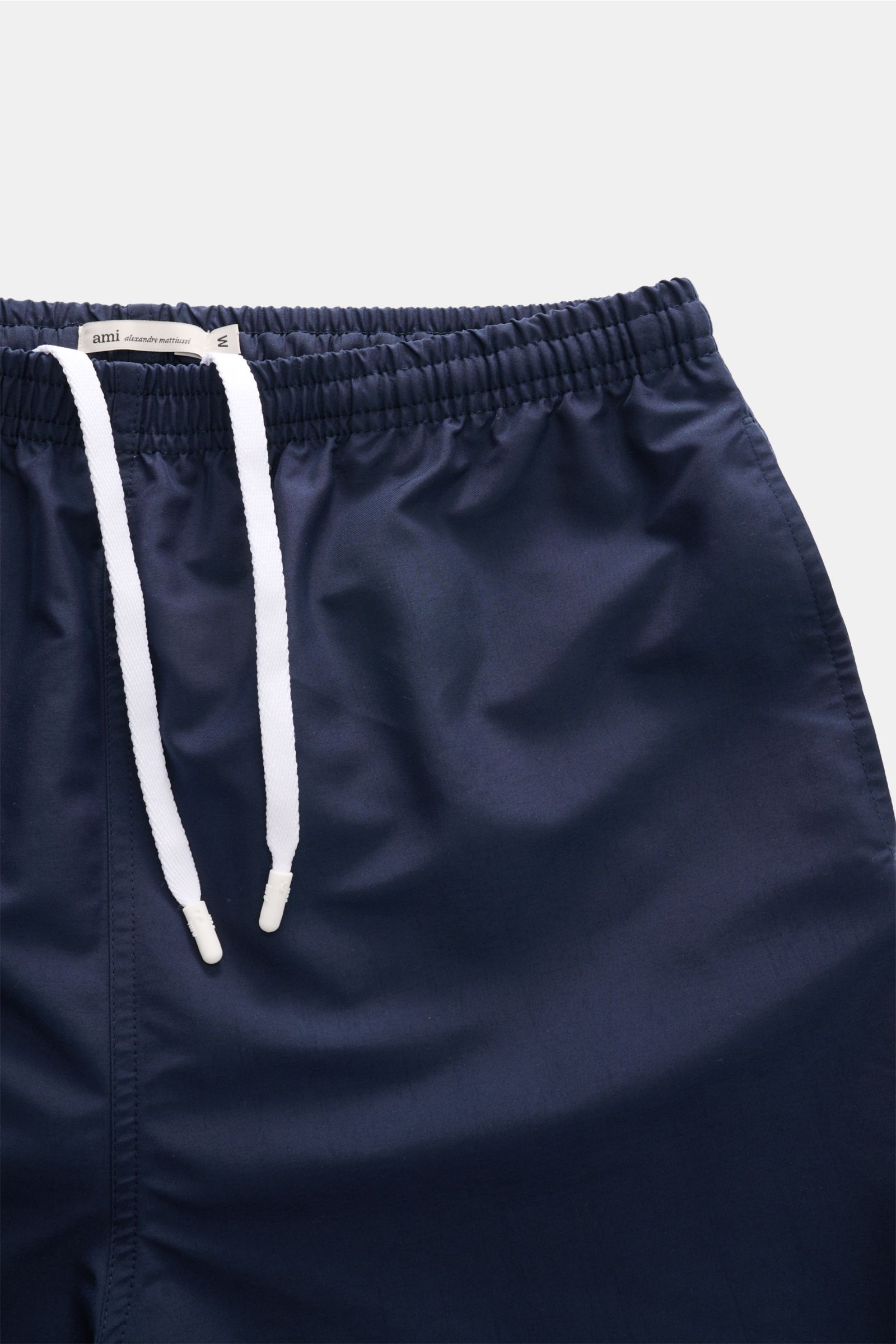 Close-up front view of Ami Paris Swim shorts navy showing elasticated waistband with white drawstring and smooth navy microfibre fabric.

Perfect for beach and pool: These swim shorts by AMI PARIS combine sporty style with fine microfibre fabric.
