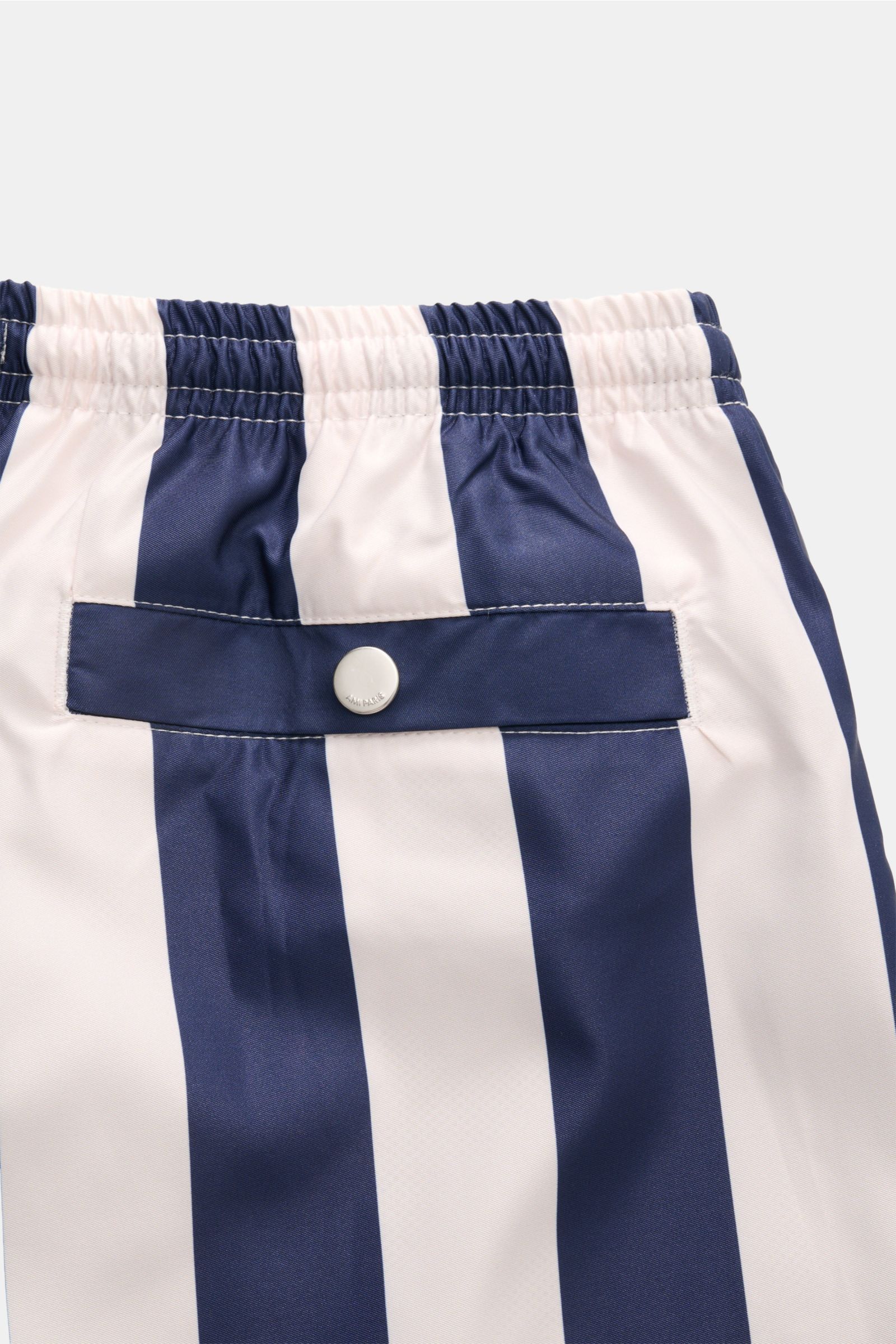 Close-up rear view of Ami Paris Badeshorts navy/weiß gestreift showing elastic waistband, back pocket with button, and vertical stripes.

Lässig durch die warme Saison: Mit den Badeshorts von AMI PARIS überzeugen Sie mit französischem Look und genießen