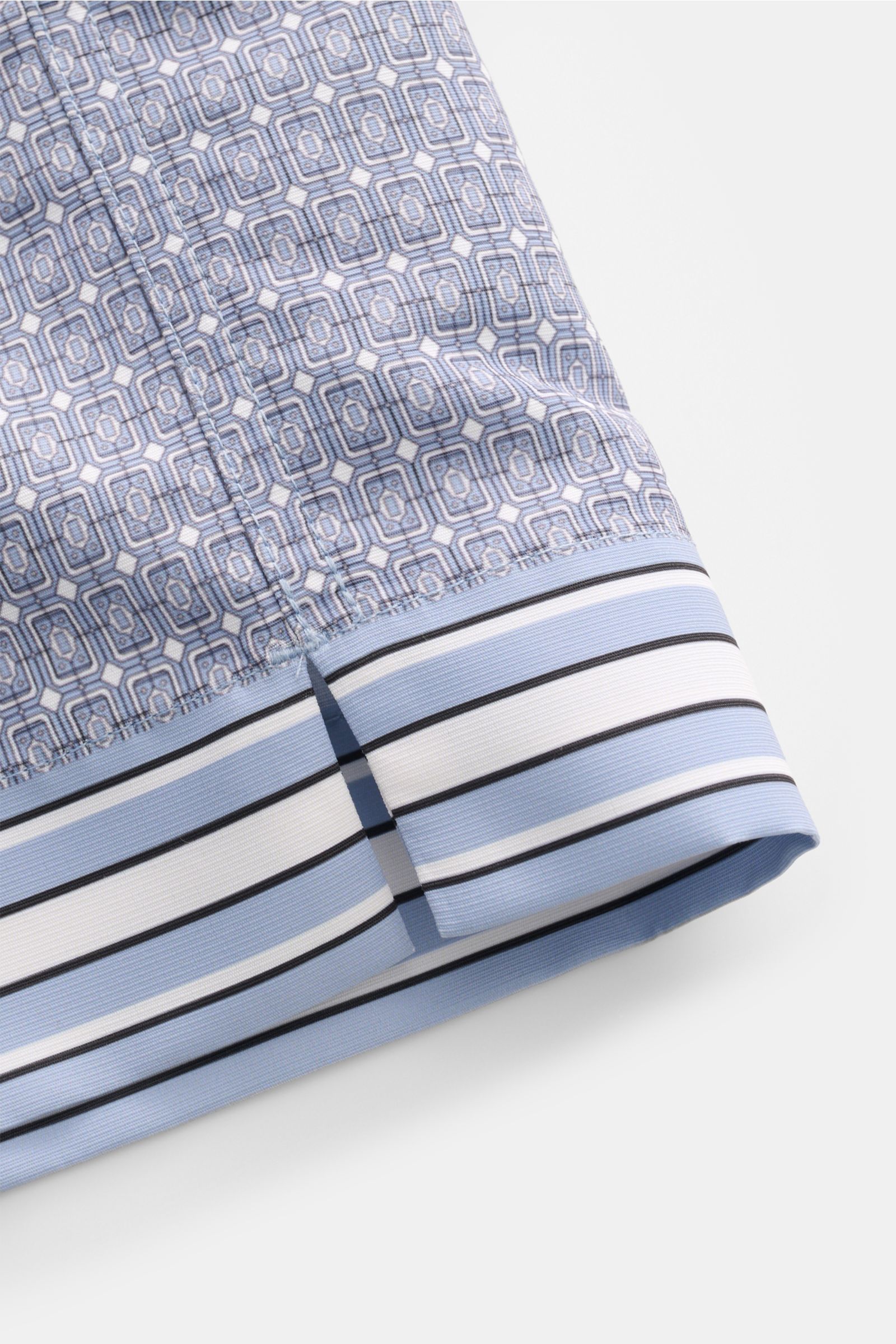 Ché Badeshorts 'Lucena' rauchblau/weiß gemustert, Detailaufnahme von Naht, ornamentalem Muster und Saum mit seitlichem Schlitz.