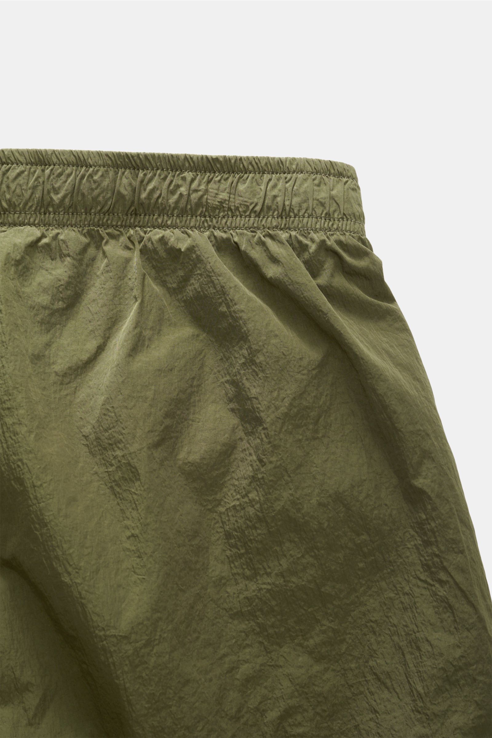 Nahaufnahme von C.P. Company Badeshorts oliv mit elastischem Bund, glänzender Oberfläche und glattem Griff, schräg von oben.