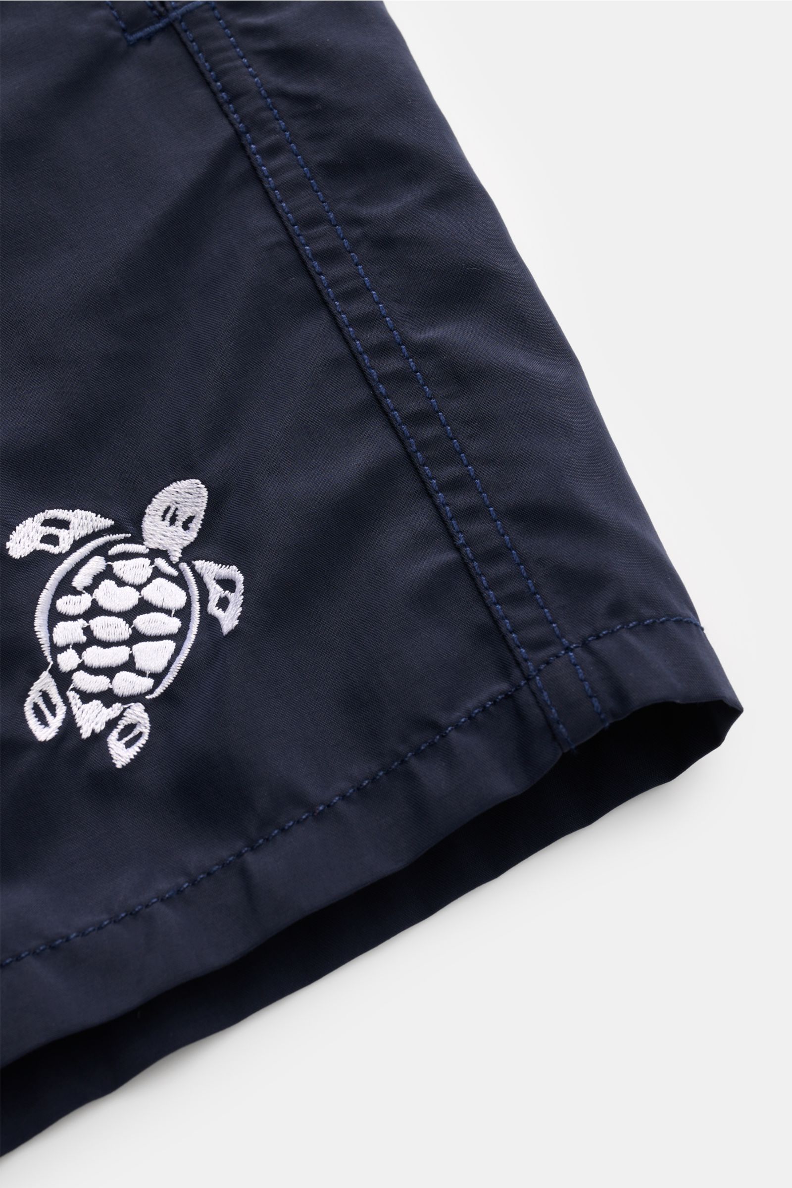 Nahaufnahme der Vilebrequin Badeshorts 'Moka' navy mit Turtle-Stitching auf hochwertiger Microfaser, seitliche Naht sichtbar.