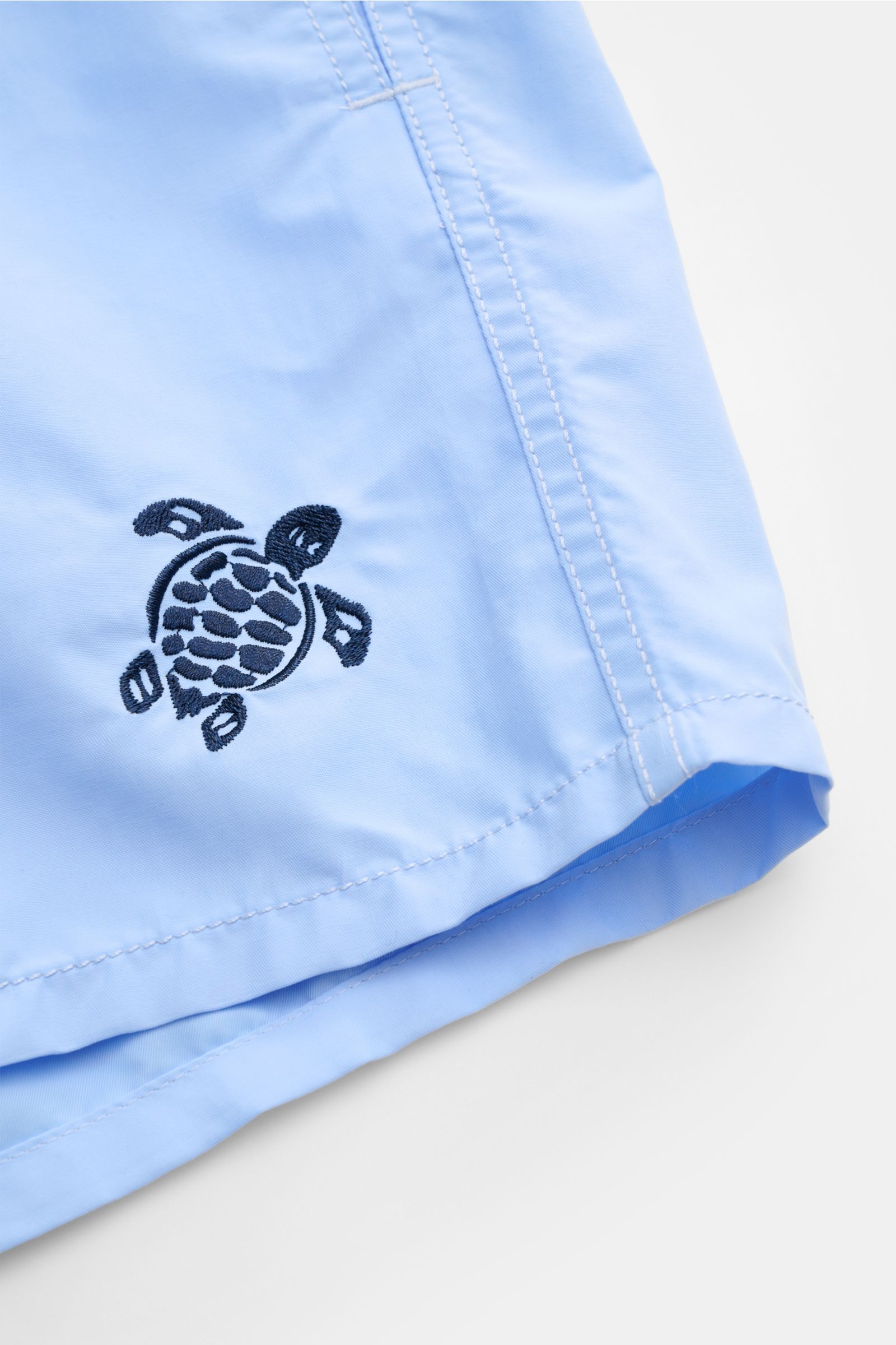 Nahaufnahme der hellblauen Vilebrequin Badeshorts 'Moka' von vorne rechts mit Turtle-Stitching, hochwertiger Microfaser und leichter Struktur.