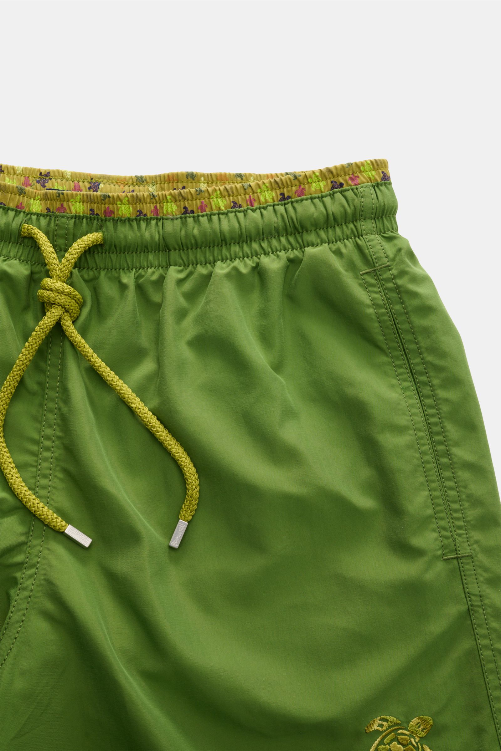 Nahaufnahme der Vilebrequin Badeshorts 'Moka' oliv von vorne, elastischer Bund mit Tunnelzug, seitliche Taschen, Turtle-Stitching am Bein.