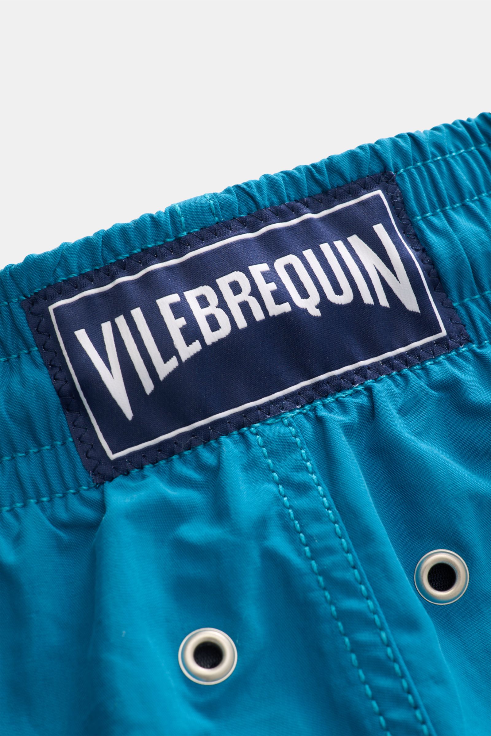 Nahaufnahme der elastischen Bundzone der Vilebrequin Badeshorts 'Moorea Magic' petrol mit blauem VILEBREQUIN-Weblabel, wasserreaktiv, aus hochwertiger Microfaser.