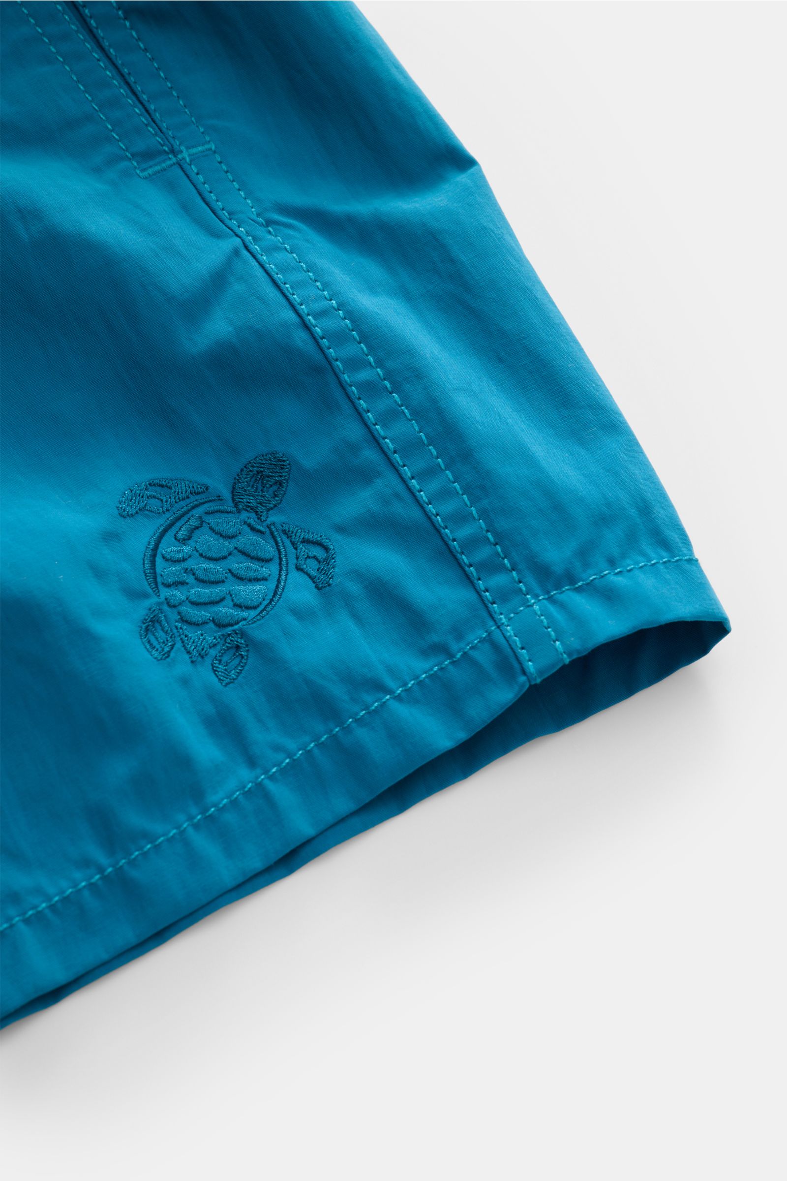 Nahaufnahme der Vilebrequin Badeshorts 'Moorea Magic' petrol, wasserreaktiv aus hochwertiger Microfaser mit gestickter Schildkröte, tonalem Stitching, Regular Fit und elastischem Bund.