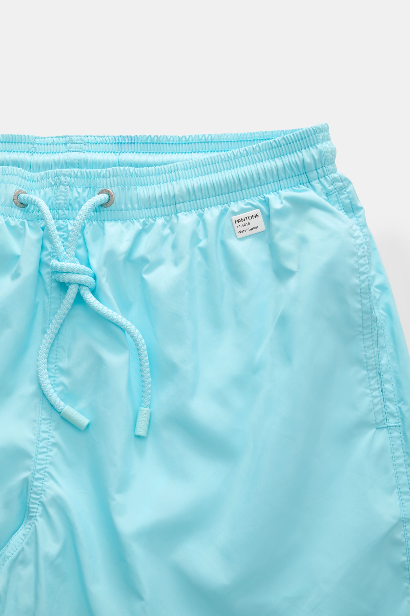 Alt-Tag (124 Zeichen): 
Nahaufnahme der MC2 Saint Barth Badeshorts 'Lightning Pantone' türkis mit elastischem Bund, Kordelzug und Pantone-Label vorne rechts.

Beschreibung zum Bildinhalt:
Das Bild zeigt die MC2 Saint Barth Badeshorts 'Lightning Pantone' i