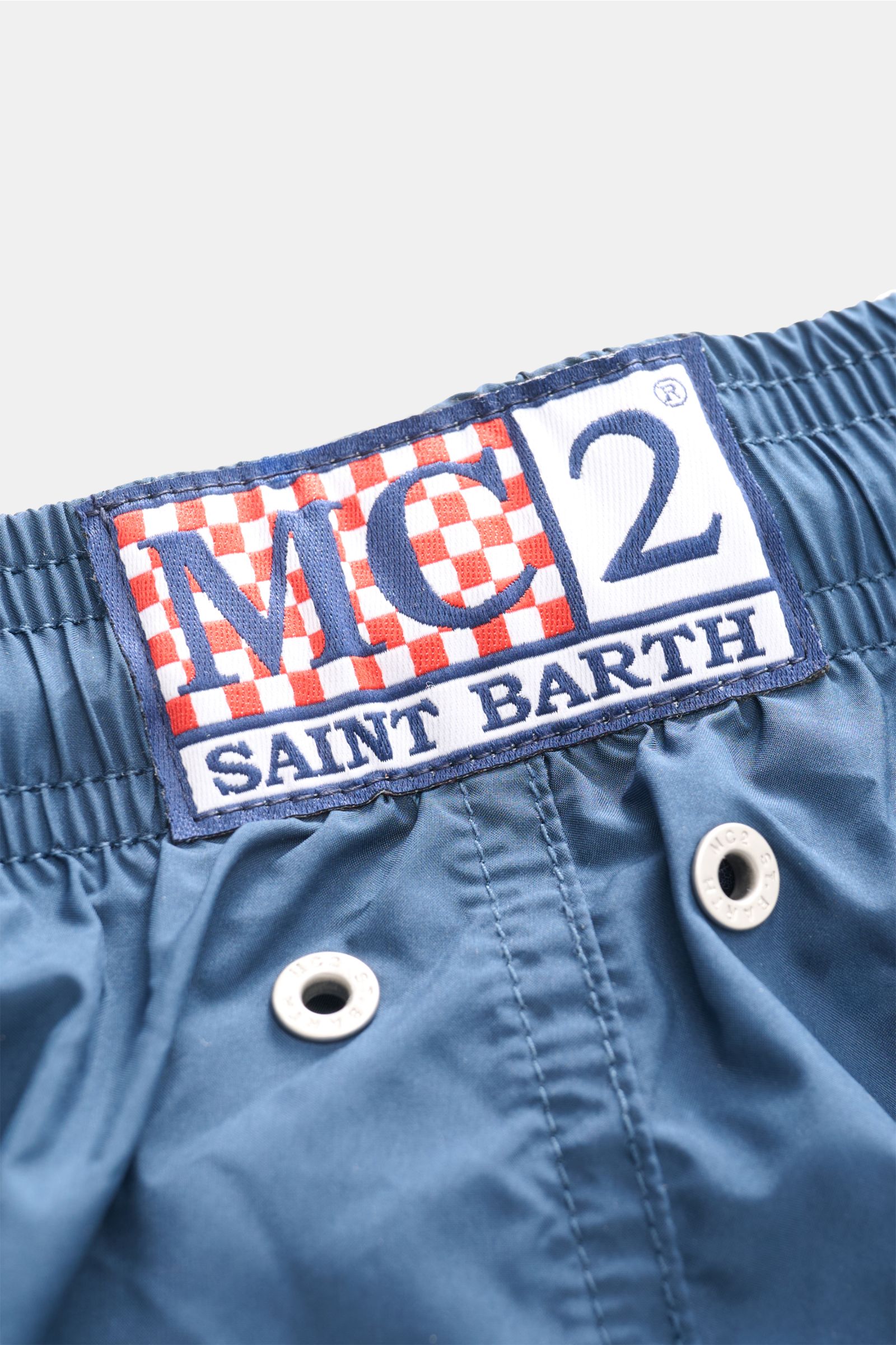 Nahaufnahme der elastischen Taille mit Logo der MC2 Saint Barth Badeshorts 'Lightning Pantone' navy aus recycelter Microfaser.