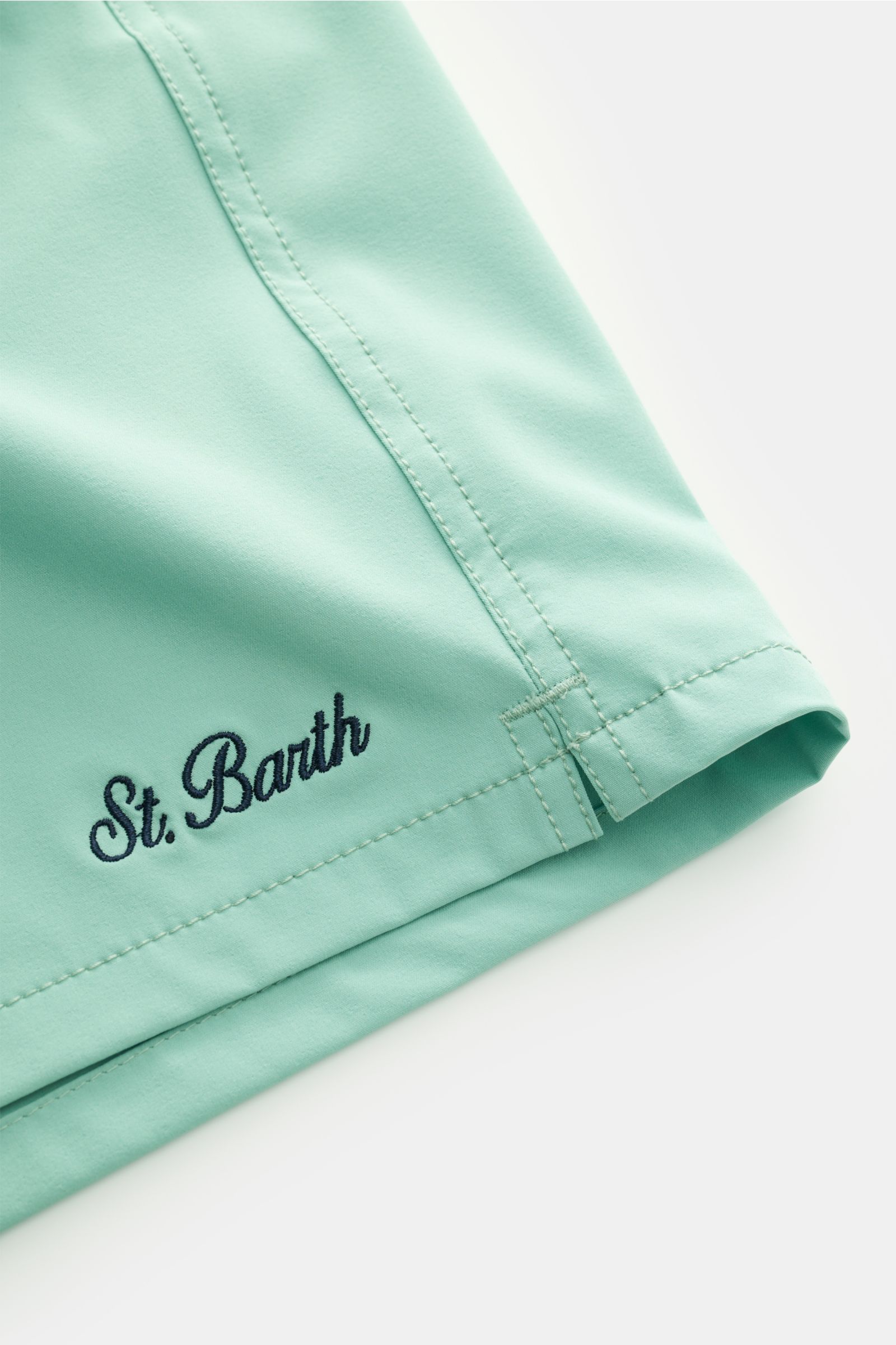Nahaufnahme der türkisen MC2 Saint Barth Badeshorts 'Comfort' von schräg oben, zeigt Saum, feine Nähte und St. Barth Stickerei.
