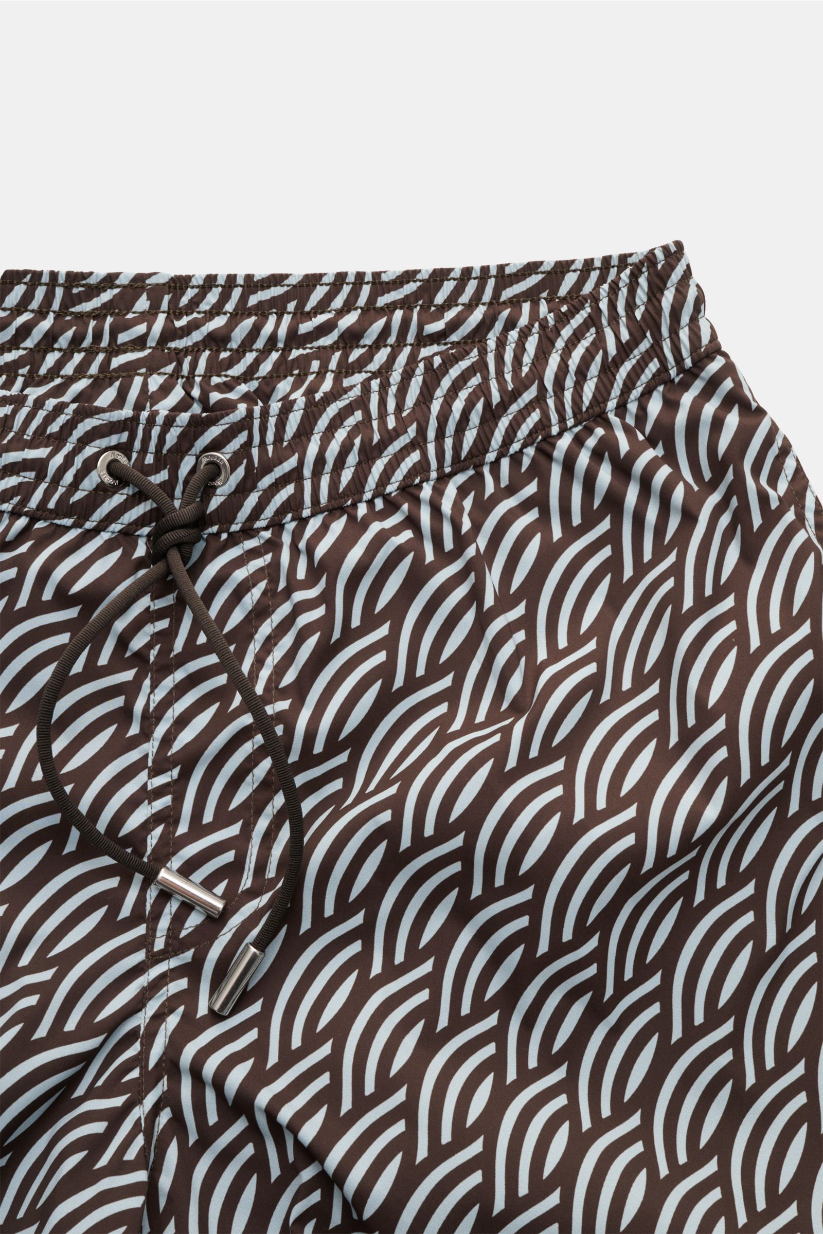 Close-up front view of Moorer Swim shorts dark brown/smoky blue patterned, featuring quick-drying microfibre, smooth feel, regular fit, elasticated waistband with drawstring, small key pocket inside, side seam pockets, back pocket with flap, and smooth li