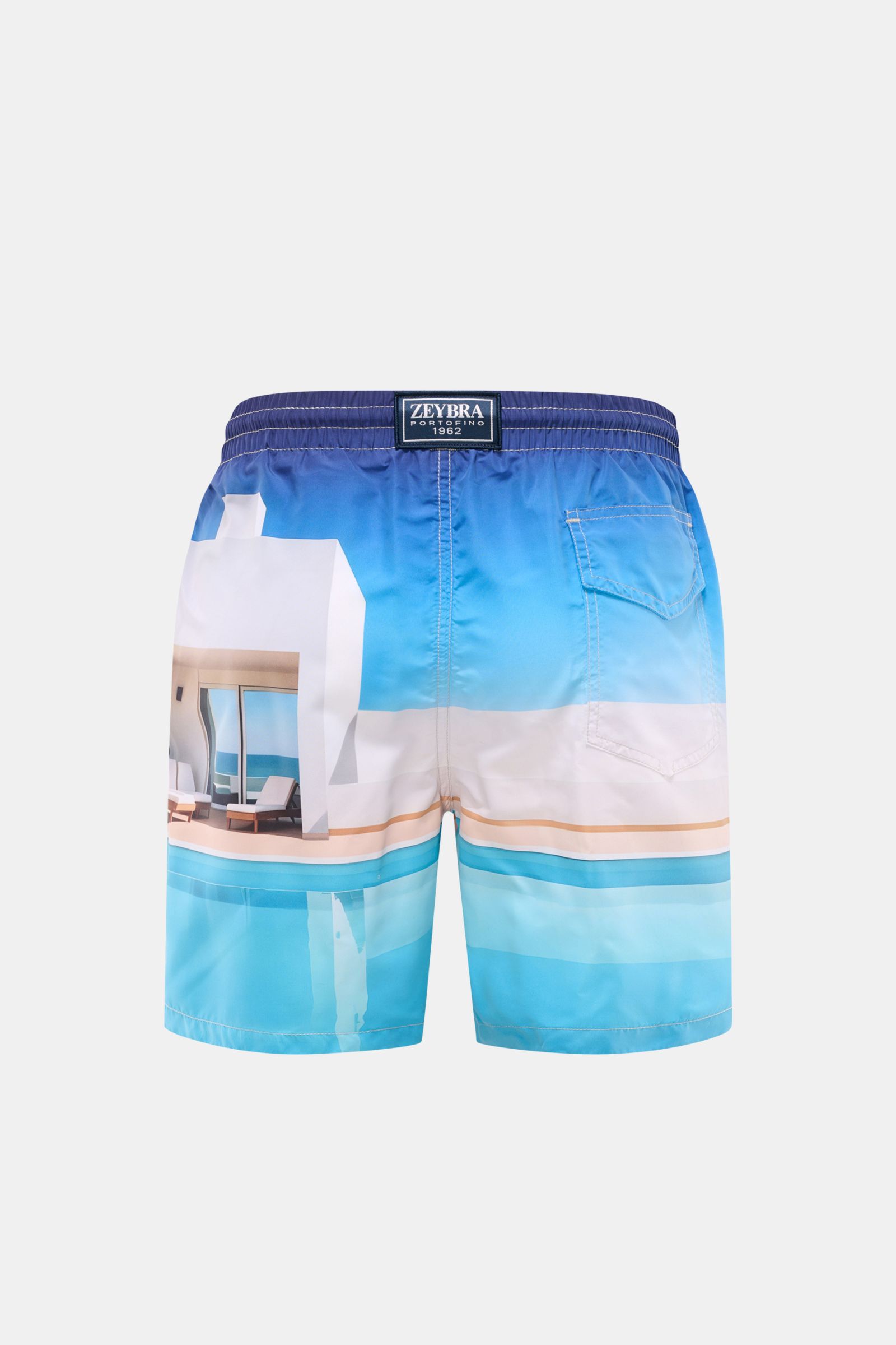 Rear view of Zeybra Portofino 1962 Badeshorts 'Villa' blau/offwhite/türkis with elastic waistband and side seam pockets, featuring a vibrant allover print of a modern villa by the pool. Sommerliches Statement: Mit ihrem markanten Allover-Print werden d