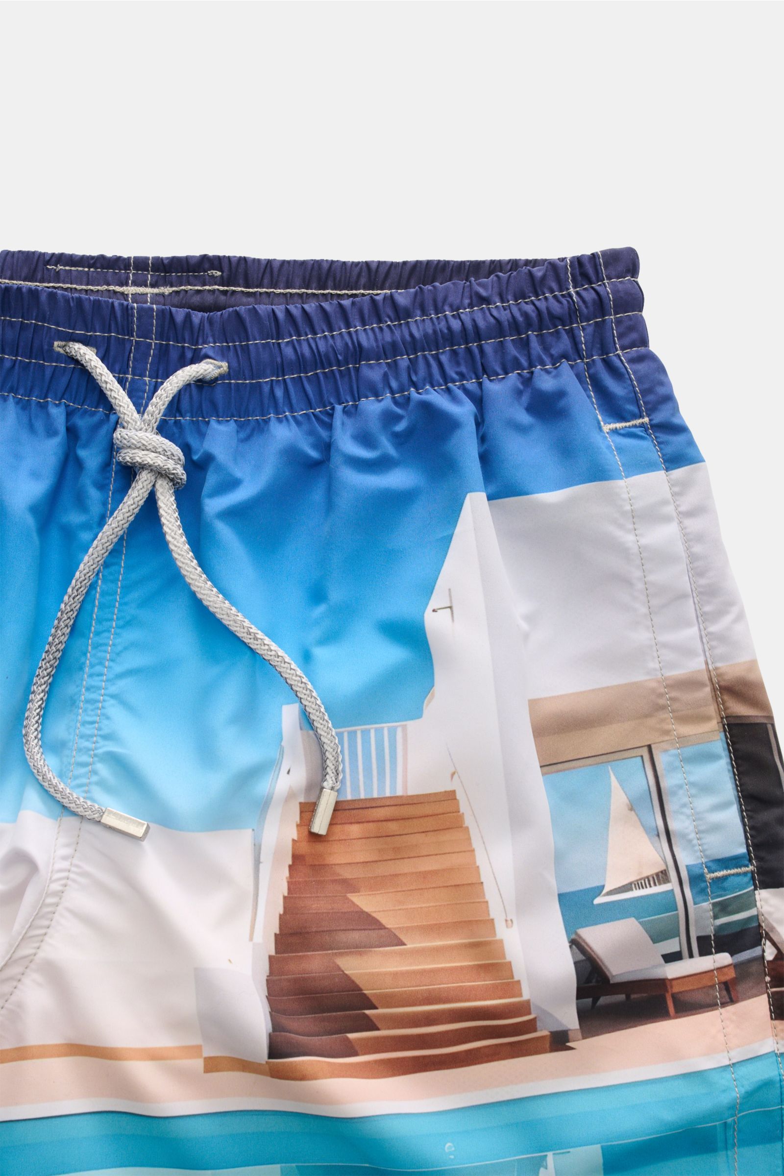 Close-up front view of Zeybra Portofino 1962 Badeshorts 'Villa' blau/offwhite/türkis with elastic waistband and drawstring, vivid beach print.  
Sommerliches Statement: Mit ihrem markanten Allover-Print werden die Badeshorts von ZEYBRA PORTOFINO 1962 z
