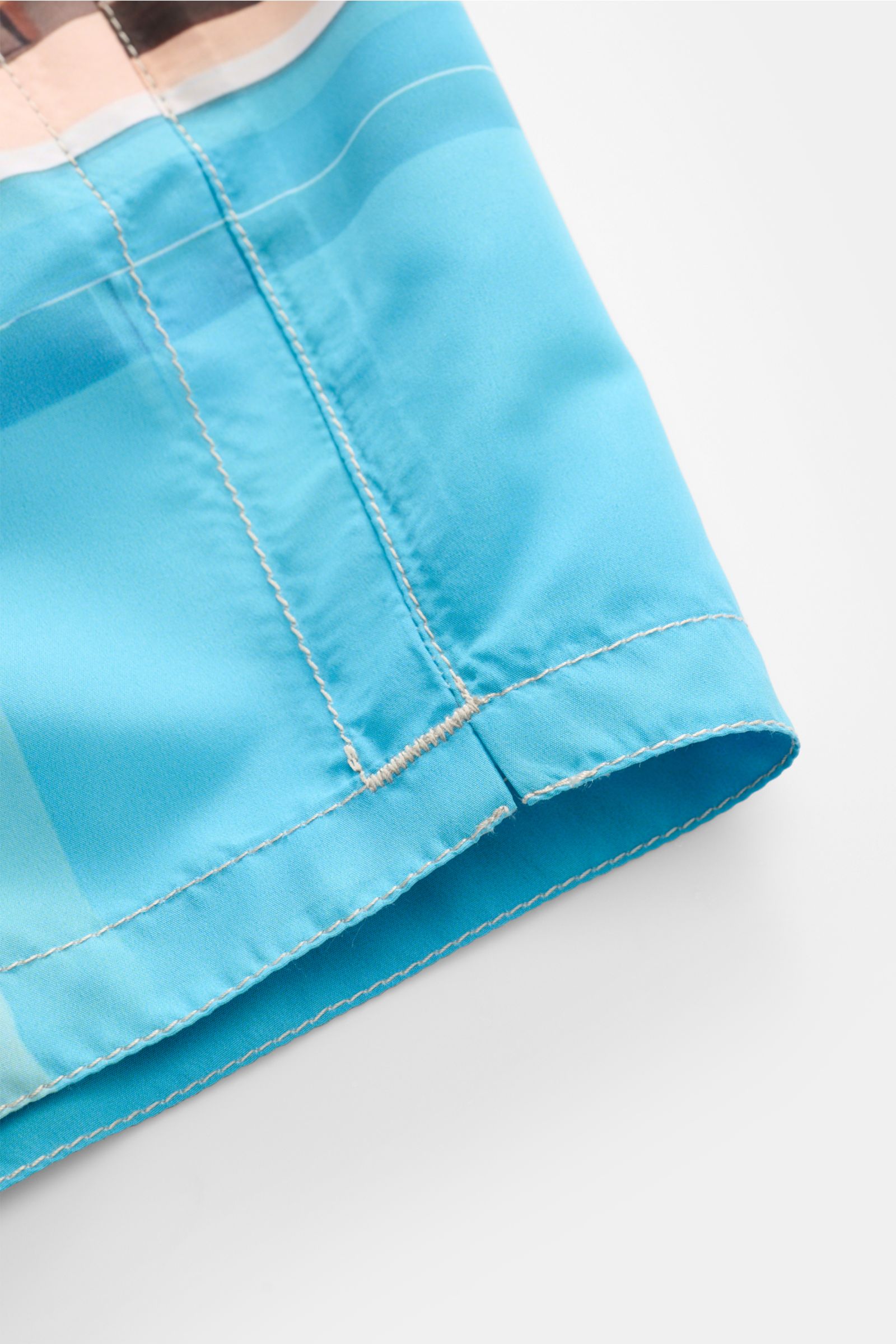 Close-up side view of the hem and stitching of Zeybra Portofino 1962 Badeshorts 'Villa' blau/offwhite/türkis. Sommerliches Statement: Mit ihrem markanten Allover-Print werden die Badeshorts von ZEYBRA PORTOFINO 1962 zum Blickfang am Strand und Pool.