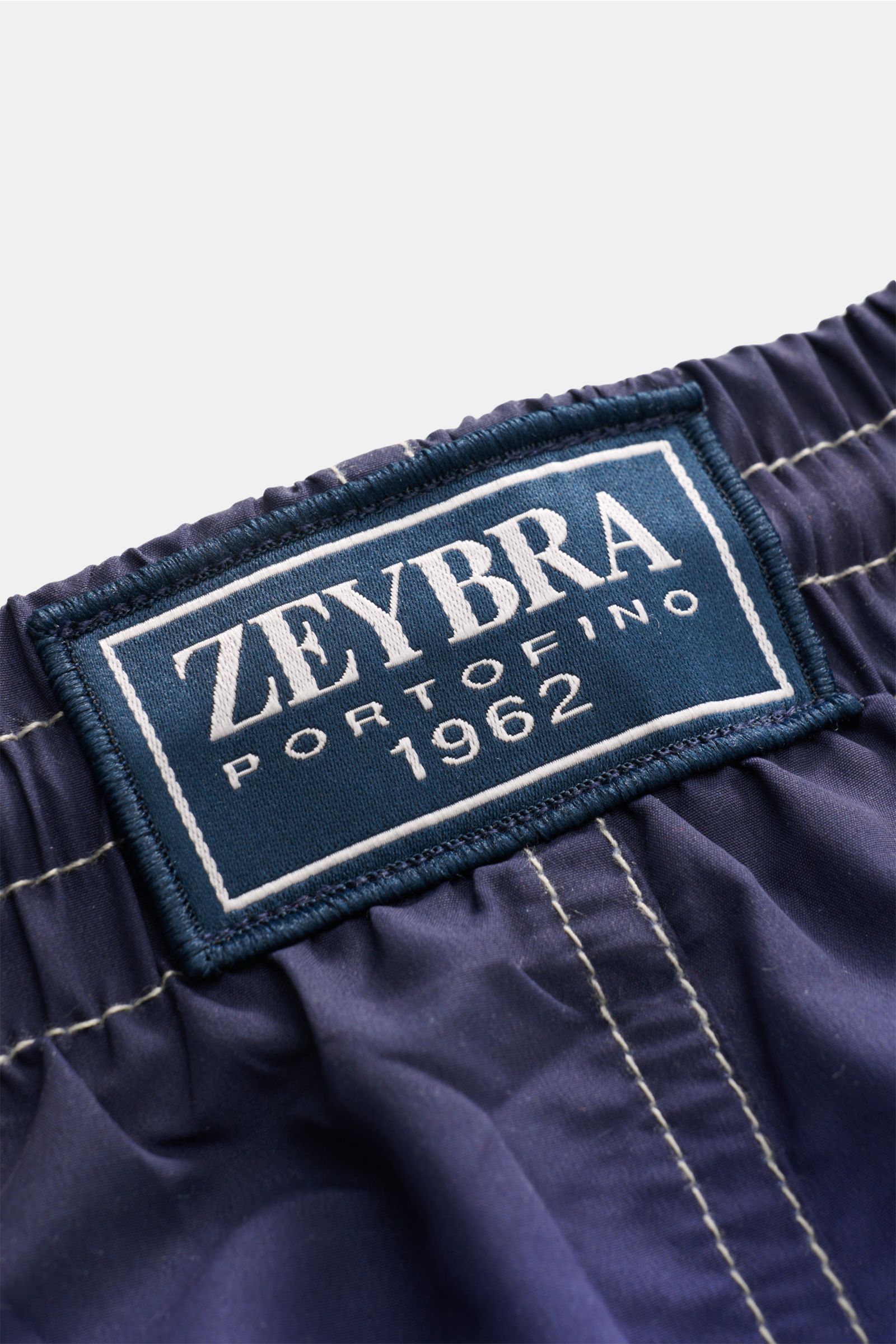 Close-up view of the elastic waistband and label of Zeybra Portofino 1962 Badeshorts 'Lisbona' multicolor, showing stitching details. Sommerliches Statement: Mit ihrem markanten Print werden die Badeshorts von ZEYBRA PORTOFINO 1962 zum Blickfang am Strand