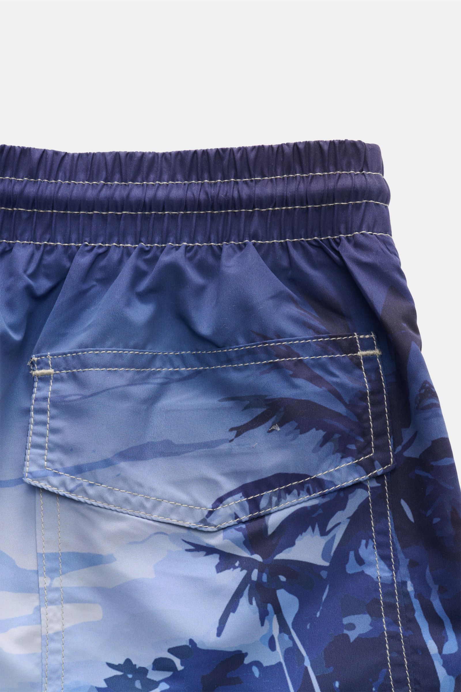 Close-up rear view of Zeybra Portofino 1962 Badeshorts 'Spiaggia' rauchblau/hellblau with elastic waistband and stitched pocket showing detailed print.

Sommerliches Statement: Mit ihrem markanten Print werden die Badeshorts von ZEYBRA PORTOFINO 1962 z