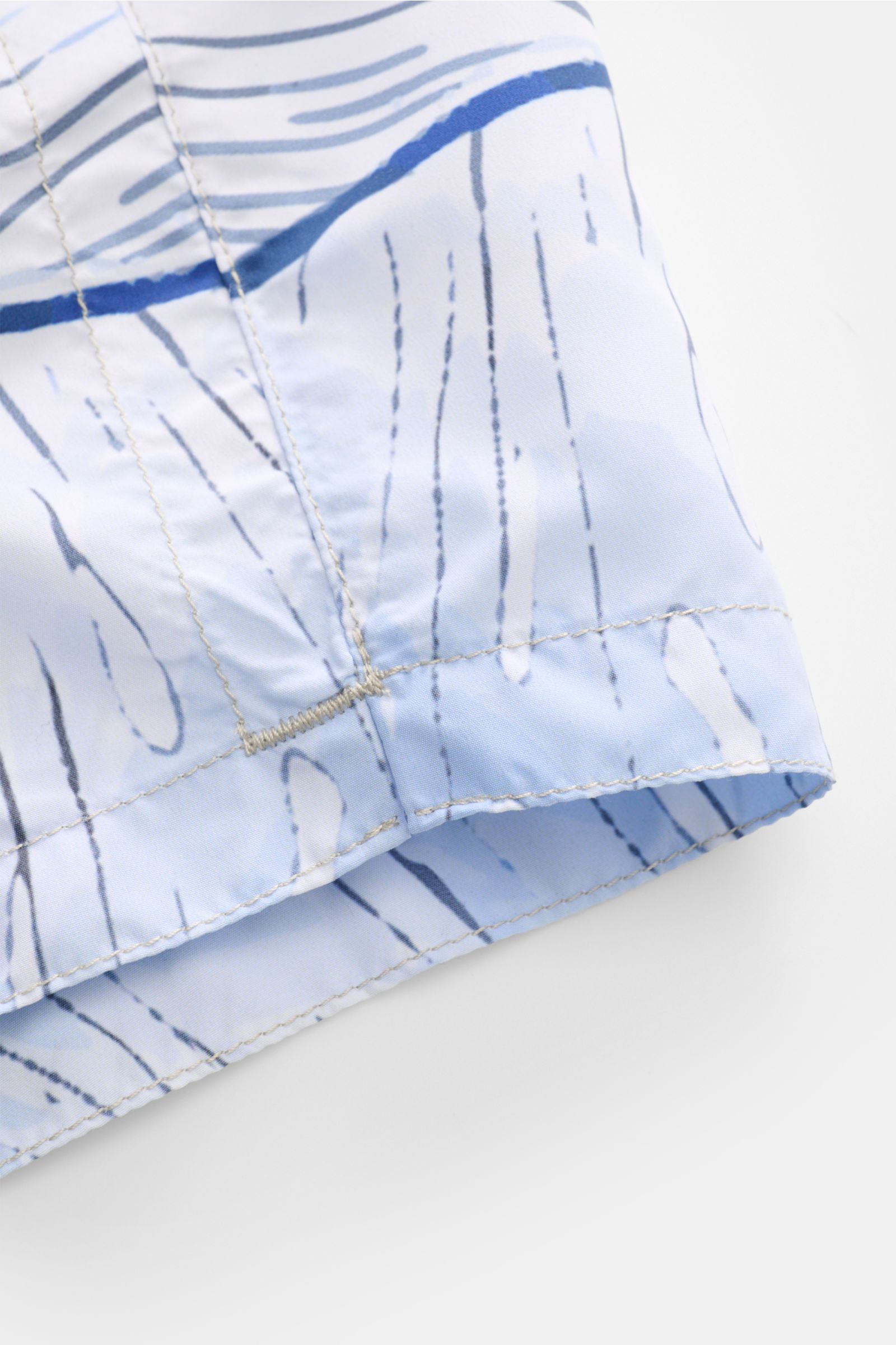 Close-up view of the hem and seam details of Zeybra Portofino 1962 Badeshorts 'Spiaggia' rauchblau/hellblau, featuring a smooth microfiber fabric with a distinctive print. Sommerliches Statement: Mit ihrem markanten Print werden die Badeshorts von ZEYB