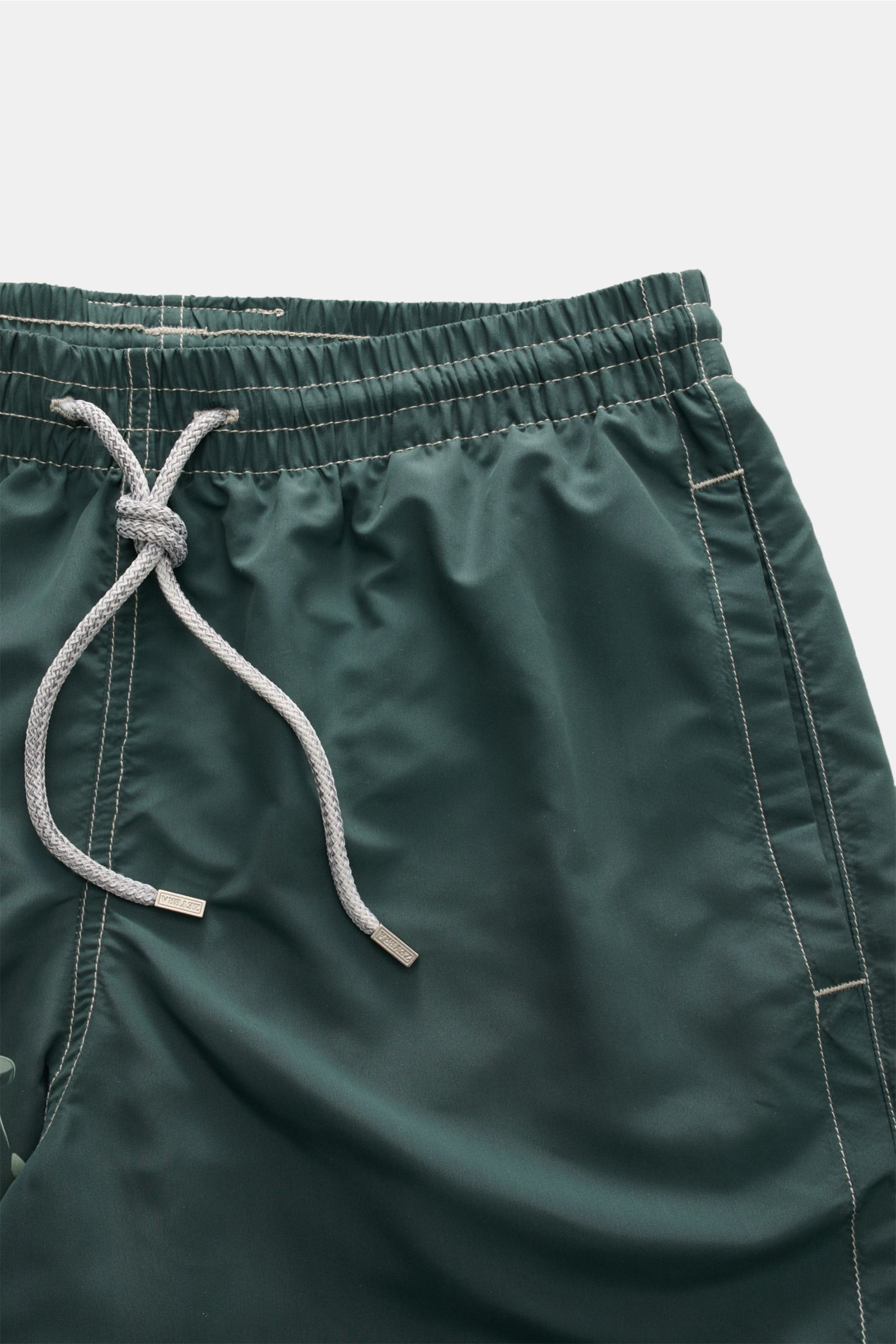 Close-up front view of Zeybra Portofino 1962 Badeshorts 'Lux Car' dunkelgrün/salbei showing elastic waistband with white drawstring and stitching details. Sommerliches Statement: Mit ihrem markanten Print werden die Badeshorts von ZEYBRA PORTOFINO 1962