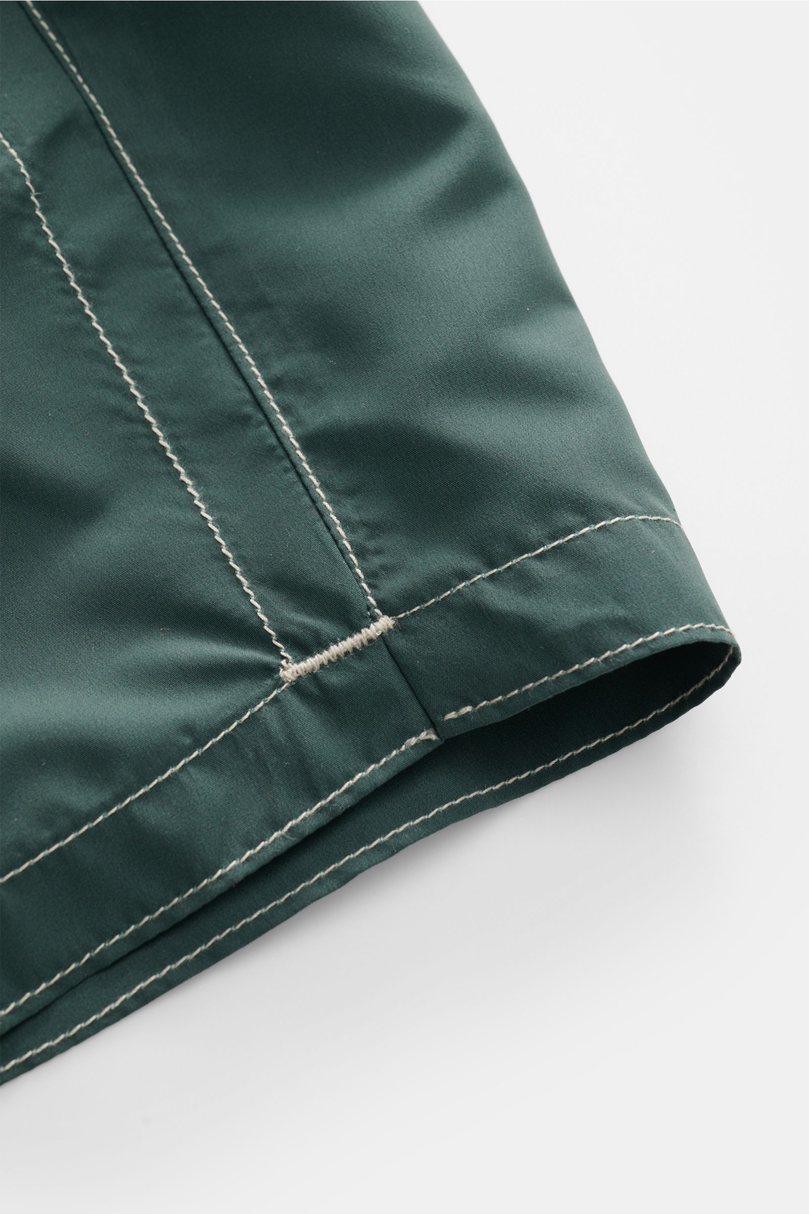 Close-up detail of the hem and stitching of Zeybra Portofino 1962 Badeshorts 'Lux Car' dunkelgrün/salbei, photographed from a side angle. Sommerliches Statement: Mit ihrem markanten Print werden die Badeshorts von ZEYBRA PORTOFINO 1962 zum Blickfang am