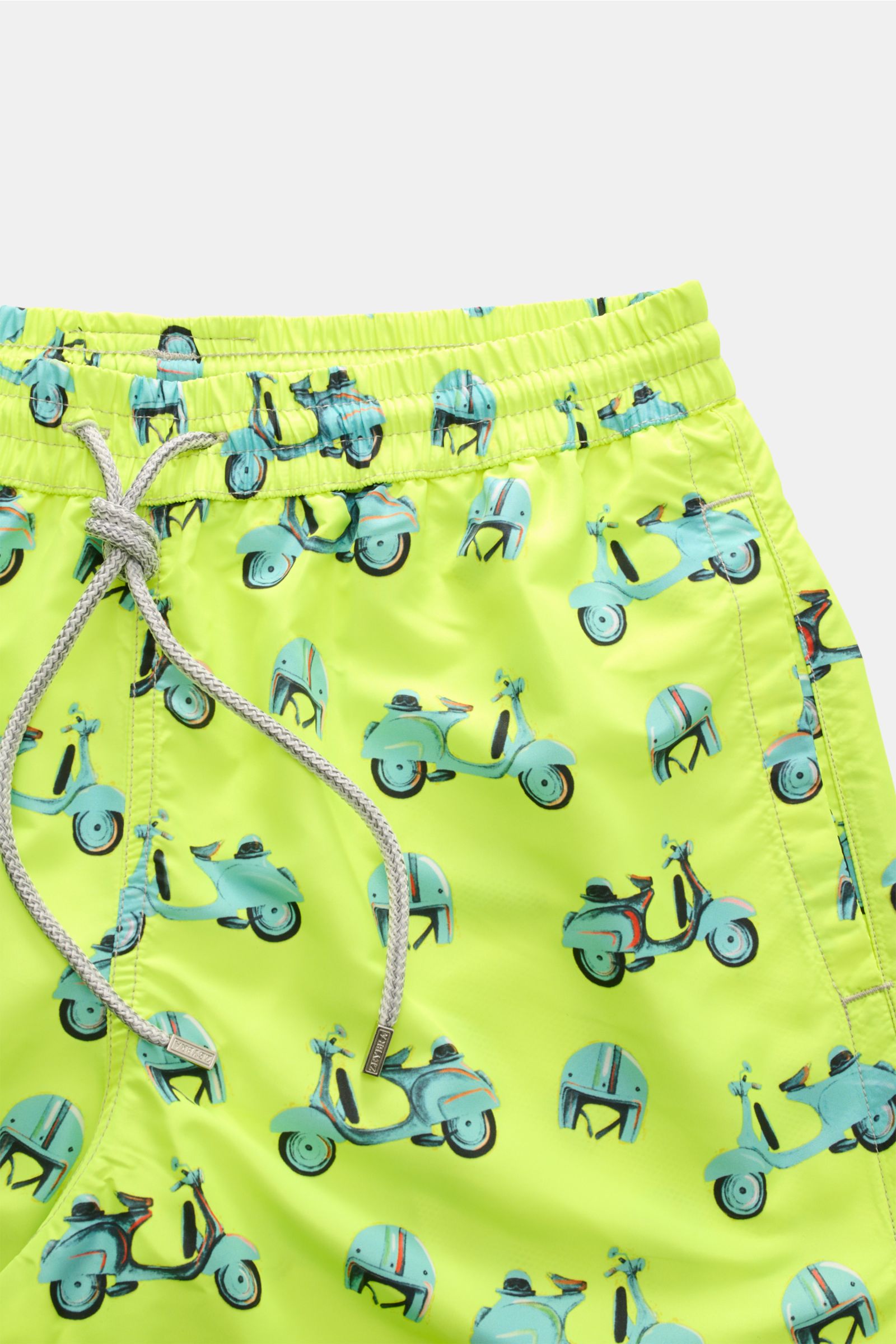 Close-up front view of Zeybra Portofino 1962 Badeshorts 'Scooter' neongelb/hellblau gemustert with blue scooter and helmet print on neon yellow fabric, elastic waistband with drawstring.

Description: Sommerliches Statement: Mit ihrem markanten Allover