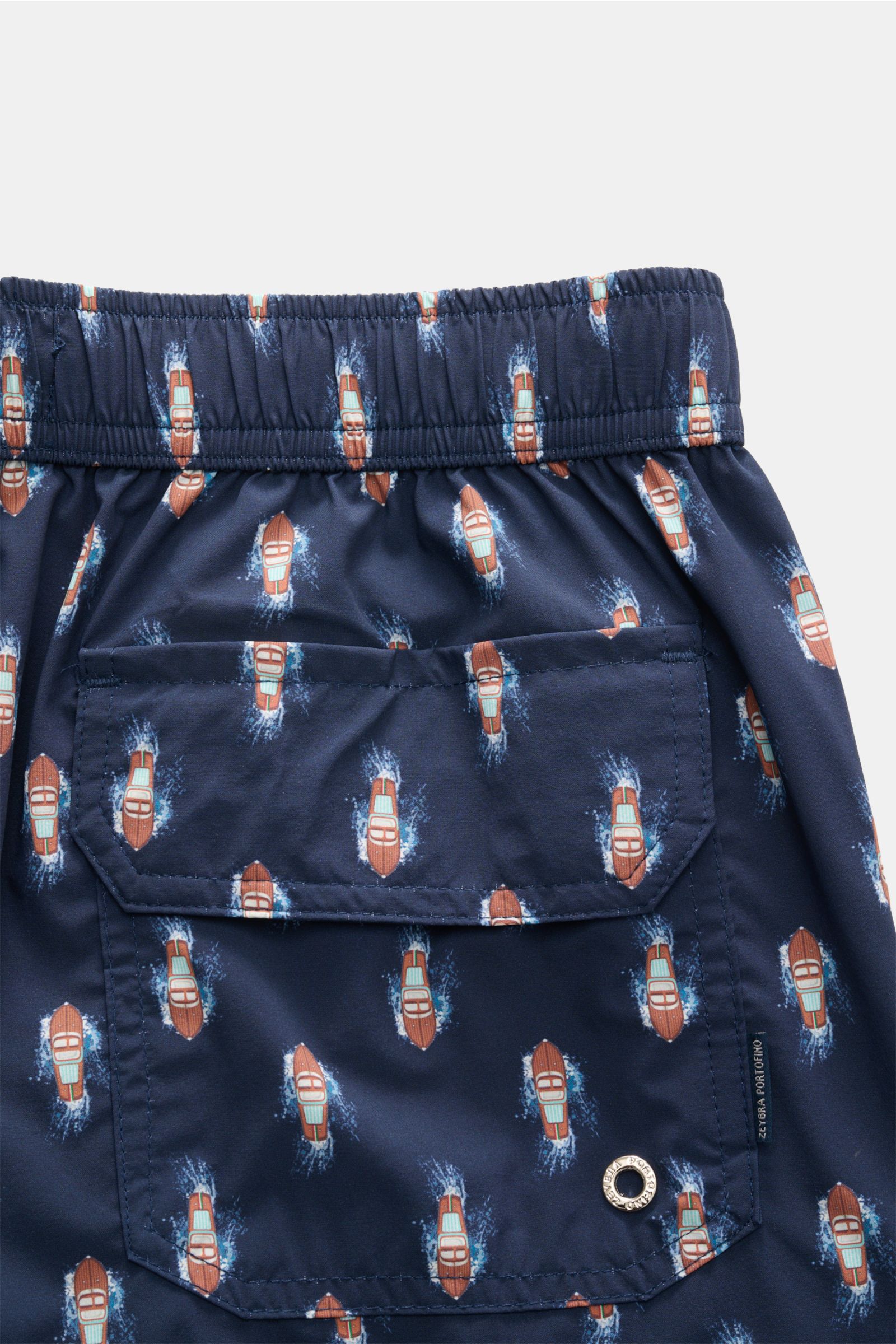 Close-up rear view of Zeybra Portofino 1962 Badeshorts 'Boat' navy/braun gemustert with elastic waistband, side and back pockets, short cut, and boat print.  
Eyecatcher für sonnige Tage: Die Badeshorts von ZEYBRA PORTOFINO 1962 überzeugen mit kurzem S