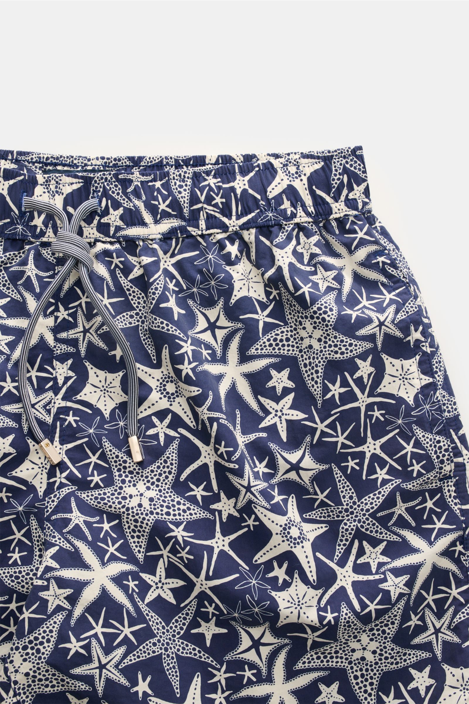 Nahaufnahme der Zeybra Portofino 1962 Badeshorts navy/offwhite gemustert mit maritimem Seestern-Print, elastischem Bund und Tunnelzug, glatter Microfaser, Regular Fit, Taschen seitlich und Gesäßtasche mit Klettverschluss, Innenfutter aus Mesh, kurze Saums