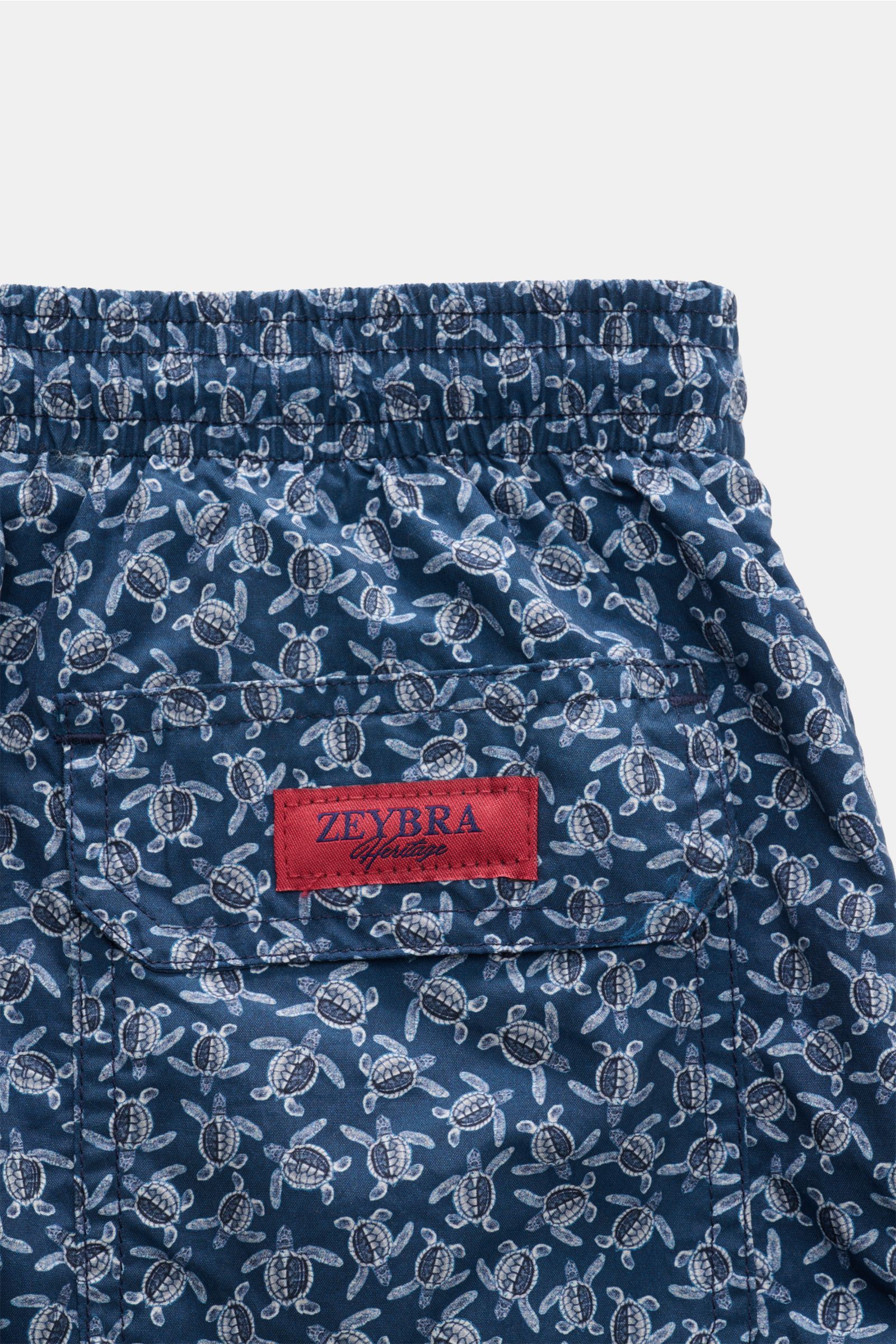 Close-up rear view of Zeybra Portofino 1962 Badeshorts 'Tatarughe' navy/blau gemustert, featuring elastic waistband, turtle print, and red ZEYBRA Heritage label. Eyecatcher für sonnige Tage: Die Badeshorts von ZEYBRA PORTOFINO 1962 überzeugen mit kurzem S