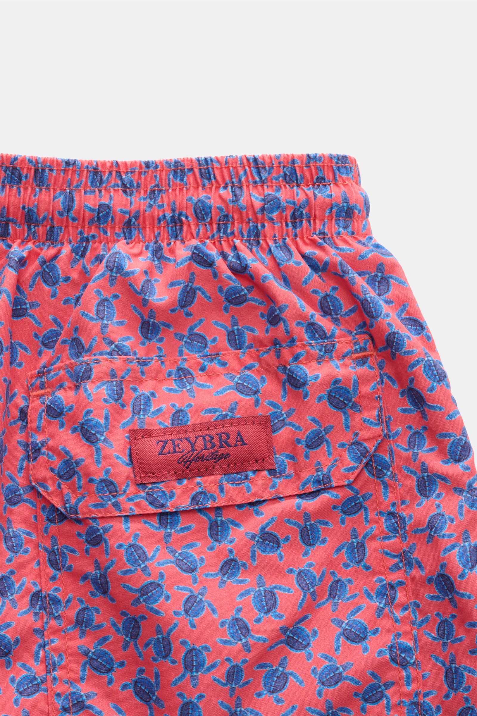 Close-up rear view of Zeybra Portofino 1962 Badeshorts 'Tatarughe' rot/blau gemustert with elastic waistband, back pocket, and turtle print.

Eyecatcher für sonnige Tage: Die Badeshorts von ZEYBRA PORTOFINO 1962 überzeugen mit kurzem Schnitt und auffäl