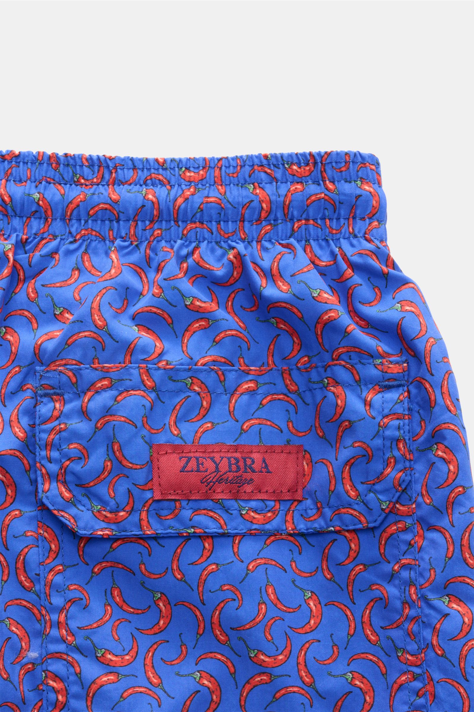 Close-up rear view of Zeybra Portofino 1962 Badeshorts 'Peperoncini' blau/rot gemustert featuring elastic waistband, red chili pepper print, and red ZEYBRA label. Eyecatcher für sonnige Tage: Die Badeshorts von ZEYBRA PORTOFINO 1962 überzeugen mit kurzem 