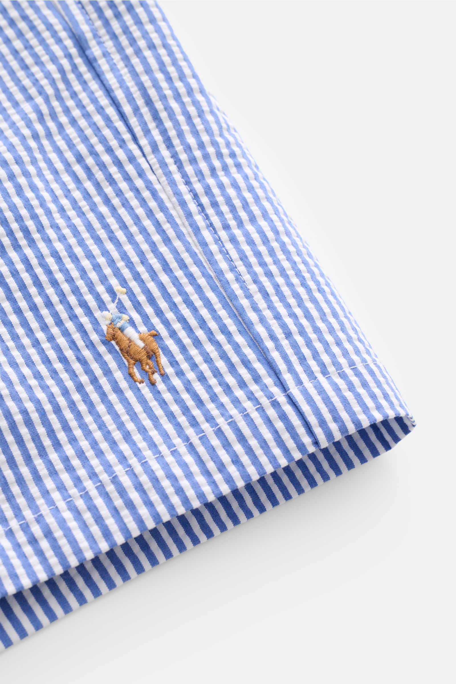 Nahaufnahme der Polo Ralph Lauren Badeshorts 'Traveler' blau/weiß gestreift mit klassischem Streifenmuster, Logo-Stitching, Regular Fit, elastischem Bund und Tunnelzug, fotografiert aus seitlicher Perspektive.