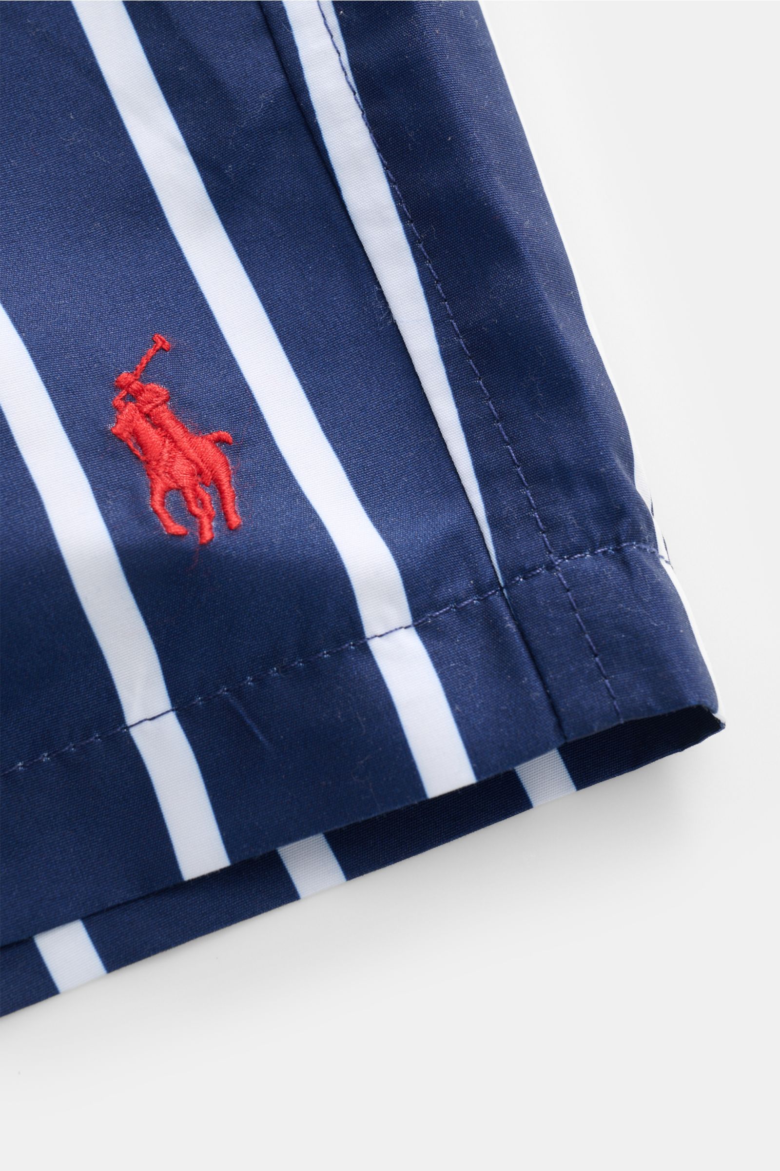 Nahaufnahme der Polo Ralph Lauren Badeshorts 'Traveler' navy/weiß gestreift, von oben fotografiert mit sichtbarem roten Logo-Stitching.