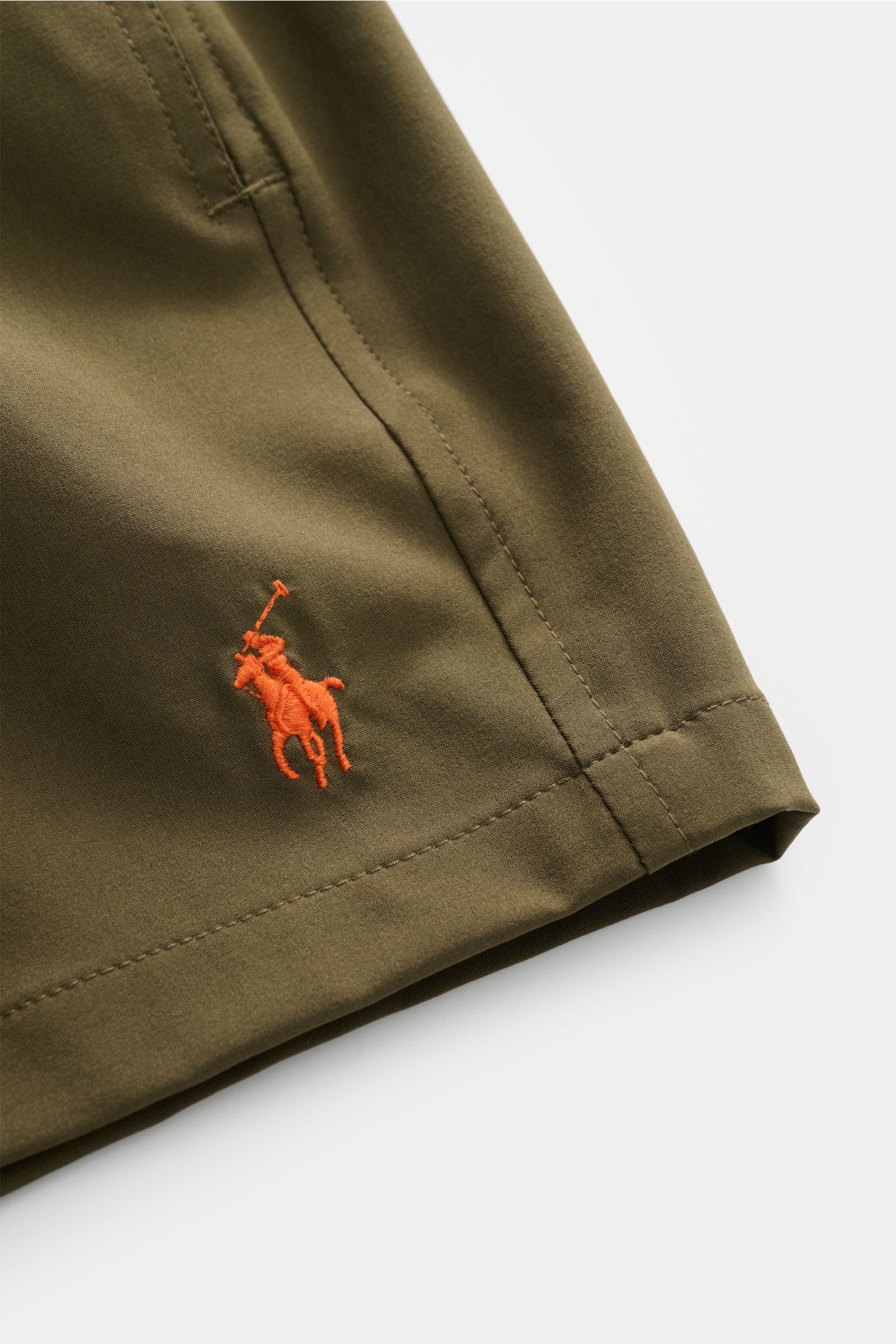 Nahaufnahme der Polo Ralph Lauren Badeshorts 'Traveler' oliv von vorne rechts, mit sichtbarem orangenem Logo-Stitching, Regular Fit und elastischem Bund.