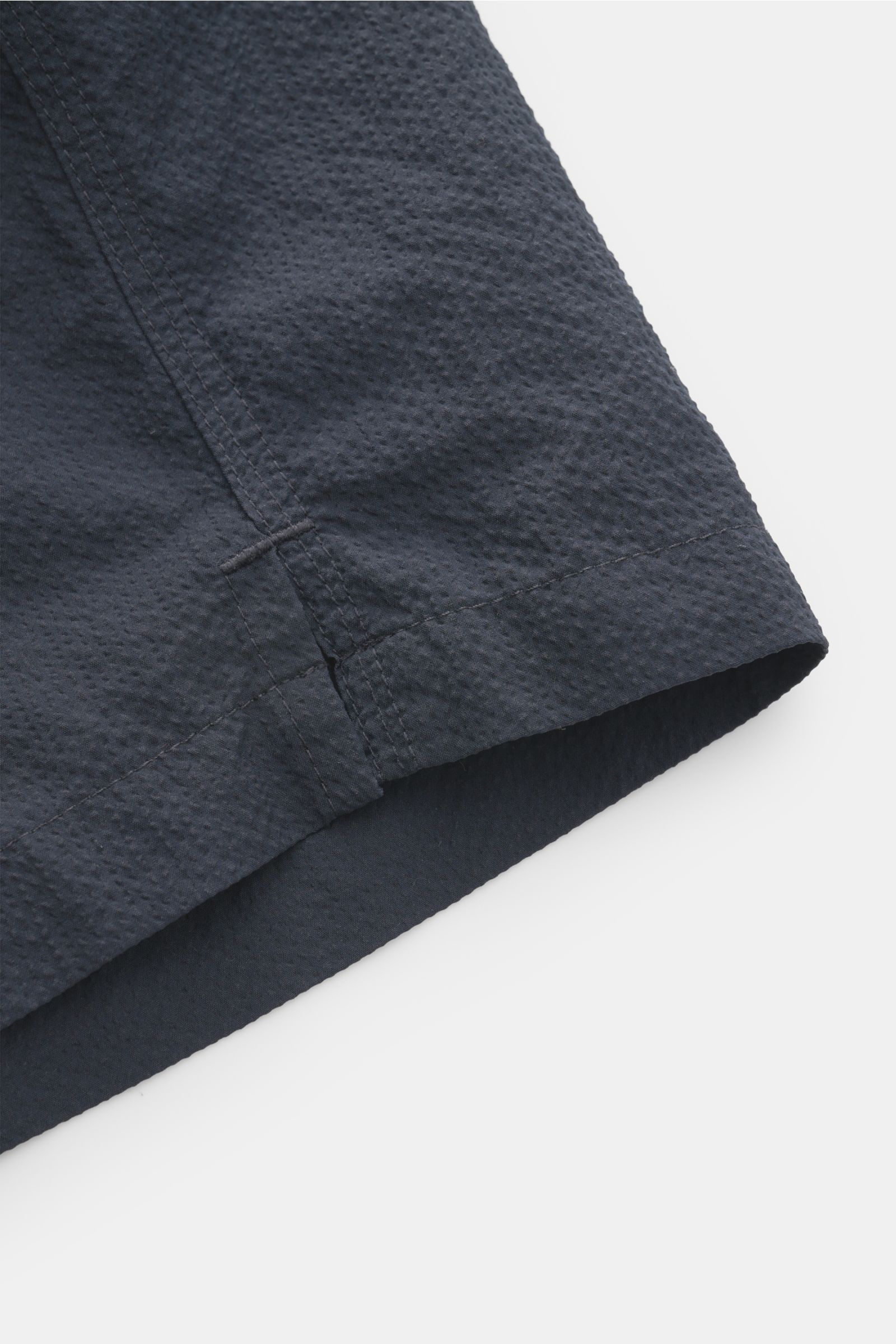 04651/ A trip in a bag Badeshorts 'Mono Seersucker' navy im Detail, Nahaufnahme der seitlichen Saumschlitze und Struktur im Seersucker-Look.