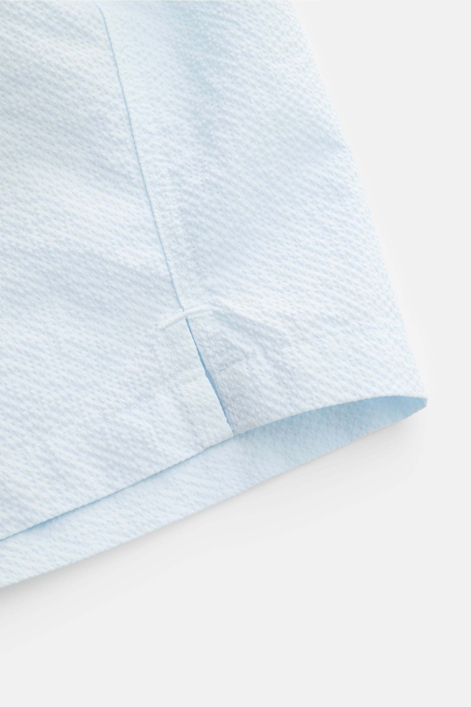 04651/ A trip in a bag Badeshorts 'Mono Seersucker' pastellblau im Seersucker-Look, Nahaufnahme der seitlichen Saumschlitze und Textur