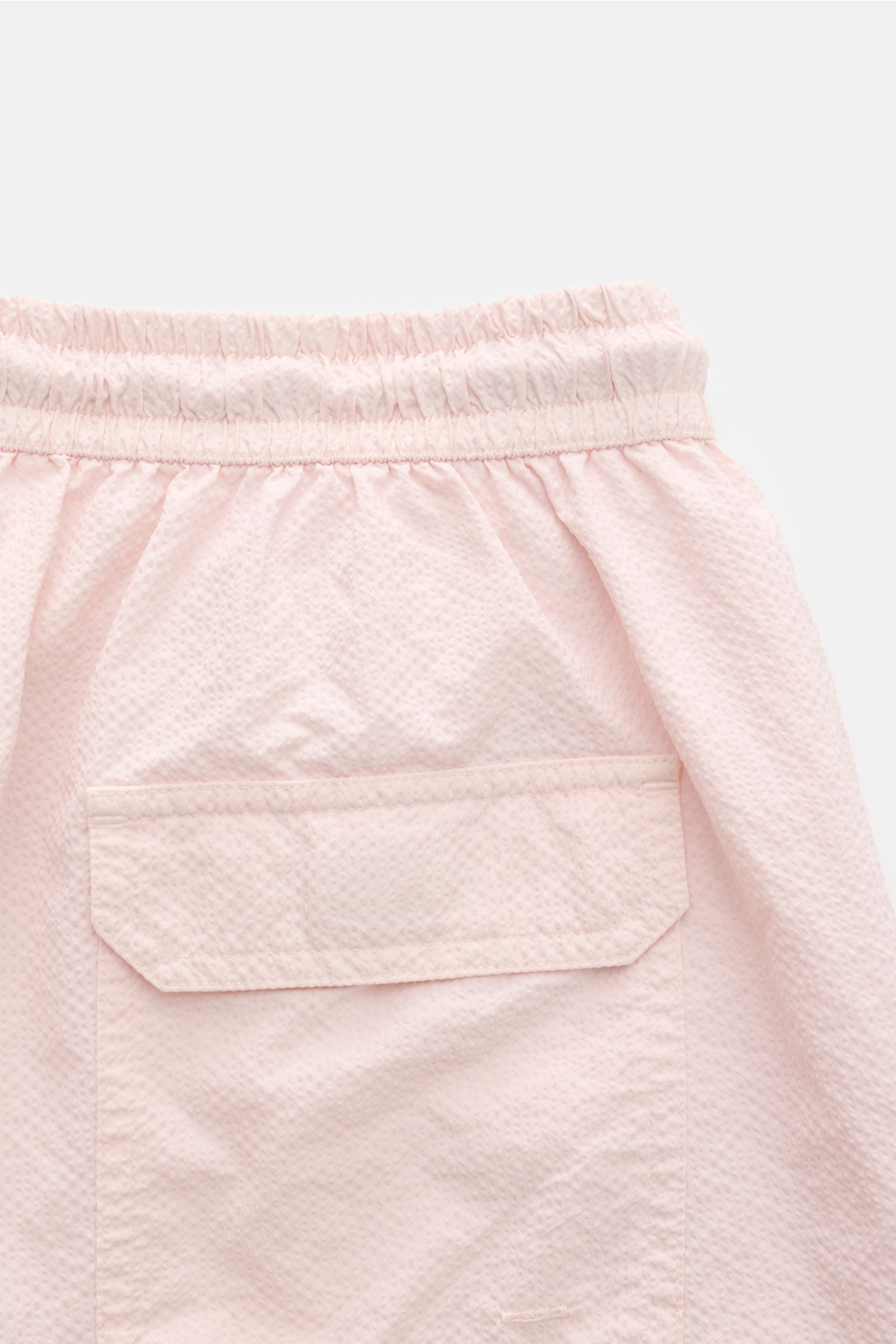 Close-up rear view of 04651/ A trip in a bag Swim shorts 'Mono Seersucker' rose in light pink with textured seersucker fabric and back pocket.

Perfect for your next summer holiday: With their design in seersucker look, these swim shorts by 04651/ A TR