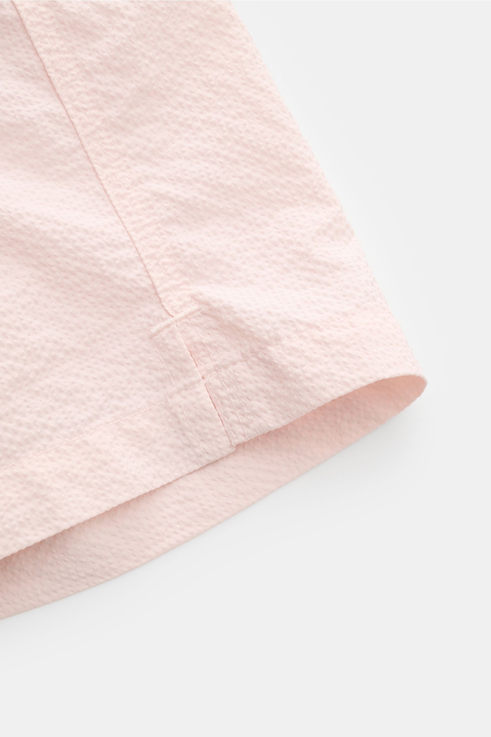 Close-up side view of the hem of 04651/ A trip in a bag Swim shorts 'Mono Seersucker' rose, showing seersucker texture.

Perfect for your next summer holiday: With their design in seersucker look, these swim shorts by 04651/ A TRIP IN A BAG are an eye-