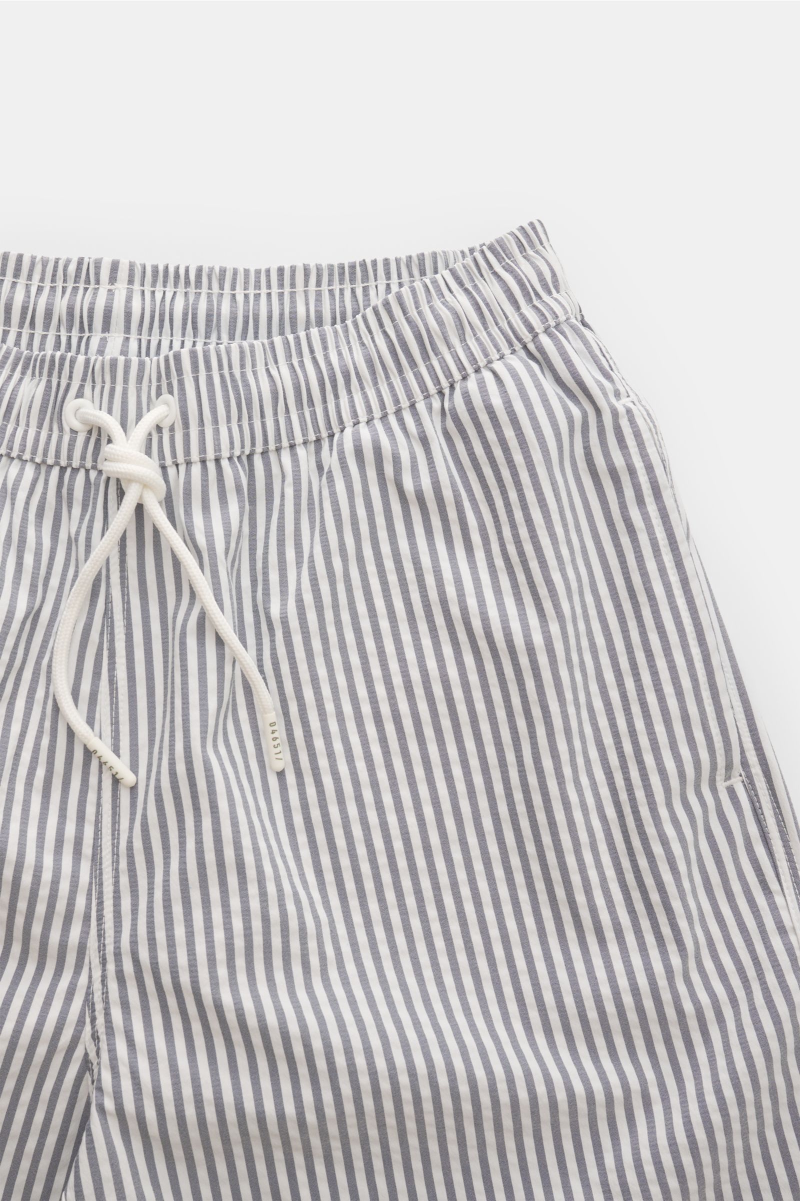 04651/ A trip in a bag Badeshorts navy/weiß gestreift, seitliche Nahaufnahme von elastischem Bund, Tunnelzug, Taschen und Seersucker-Stoff.