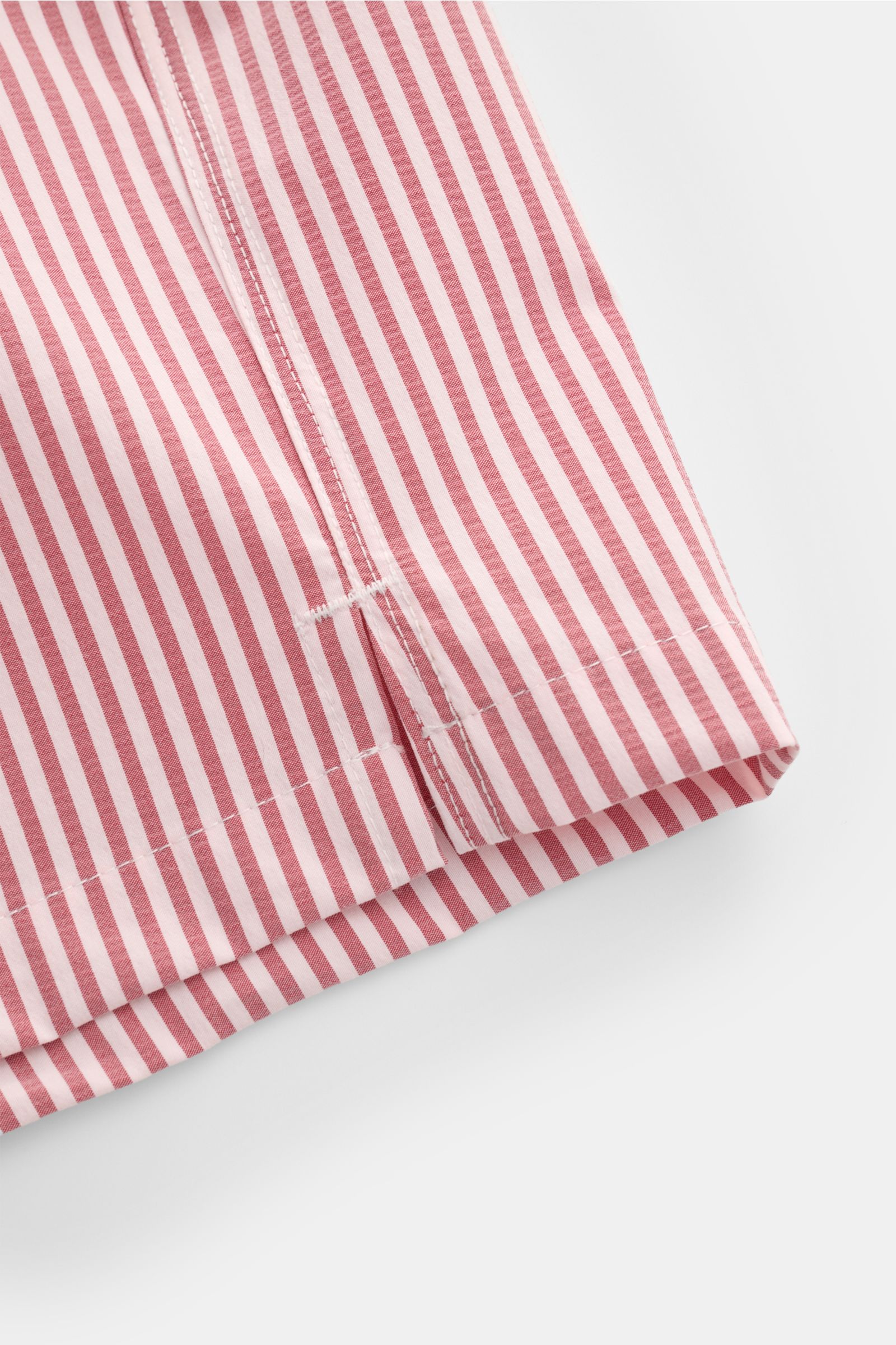 04651/ A trip in a bag Badeshorts rosé/bordeaux gestreift, Detailaufnahme Saum mit seitlichem Schlitz, leichter Seersucker-Stoff.