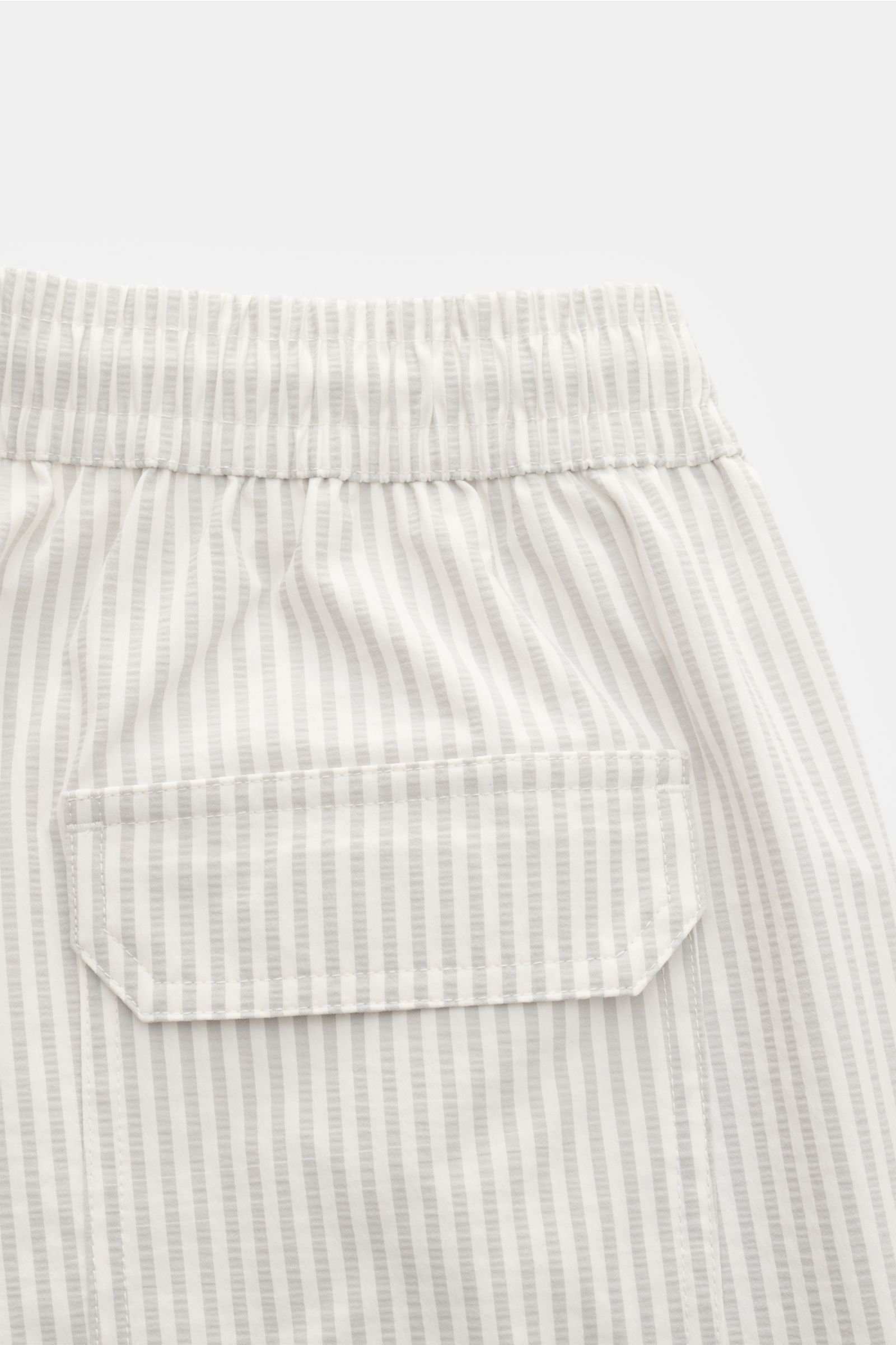 Close-up rear view of 04651/ A trip in a bag Swim shorts light grey/white striped showing elastic waistband and back pocket with flap.

Perfect for your next summer holiday: With their modern striped pattern, these swim shorts by 04651/ A TRIP IN A BAG