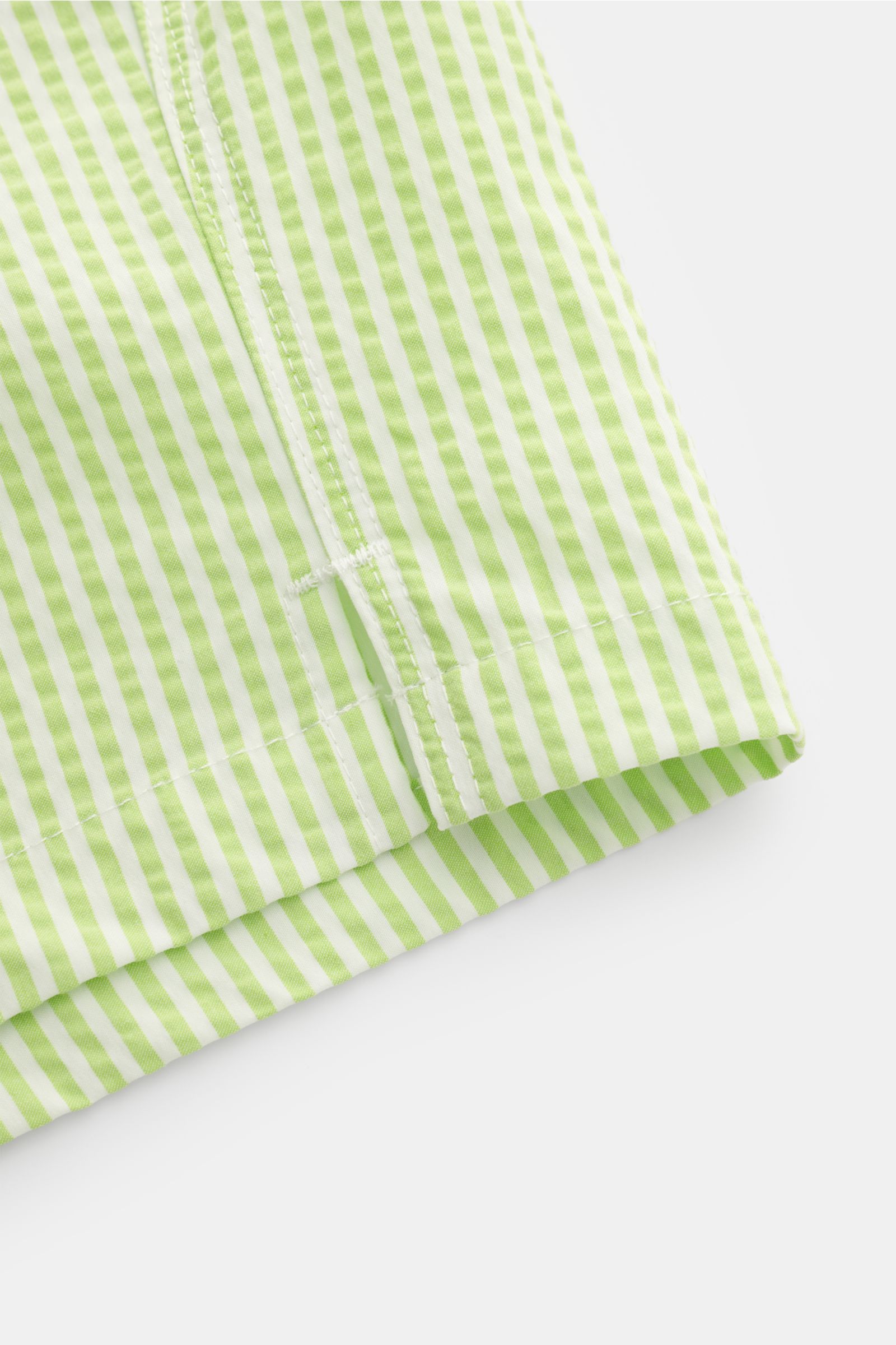 Nahaufnahme der Saumkante mit seitlichem Schlitz der 04651/ A trip in a bag Badeshorts pastellgrün/weiß gestreift aus leichtem Baumwolle-Microfaser-Seersucker.