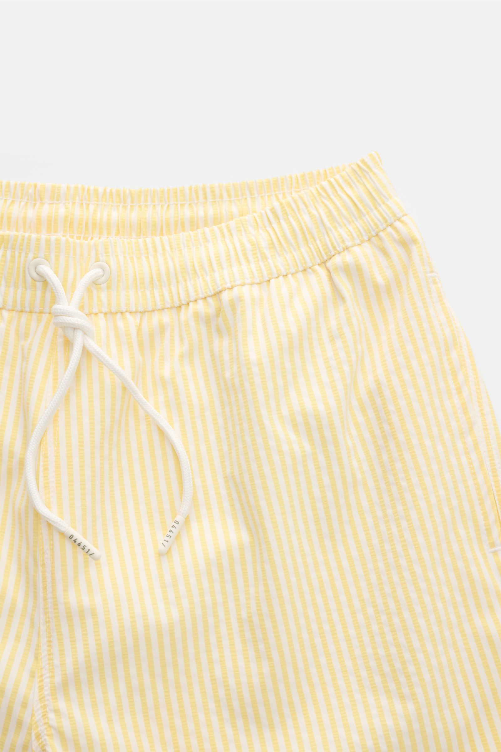 Close-up front view of 04651/ A trip in a bag Swim shorts pastel yellow/white striped with elastic waistband and drawstring.

Perfect for your next summer holiday: With their modern striped pattern, these swim shorts by 04651/ A TRIP IN A BAG are an ey