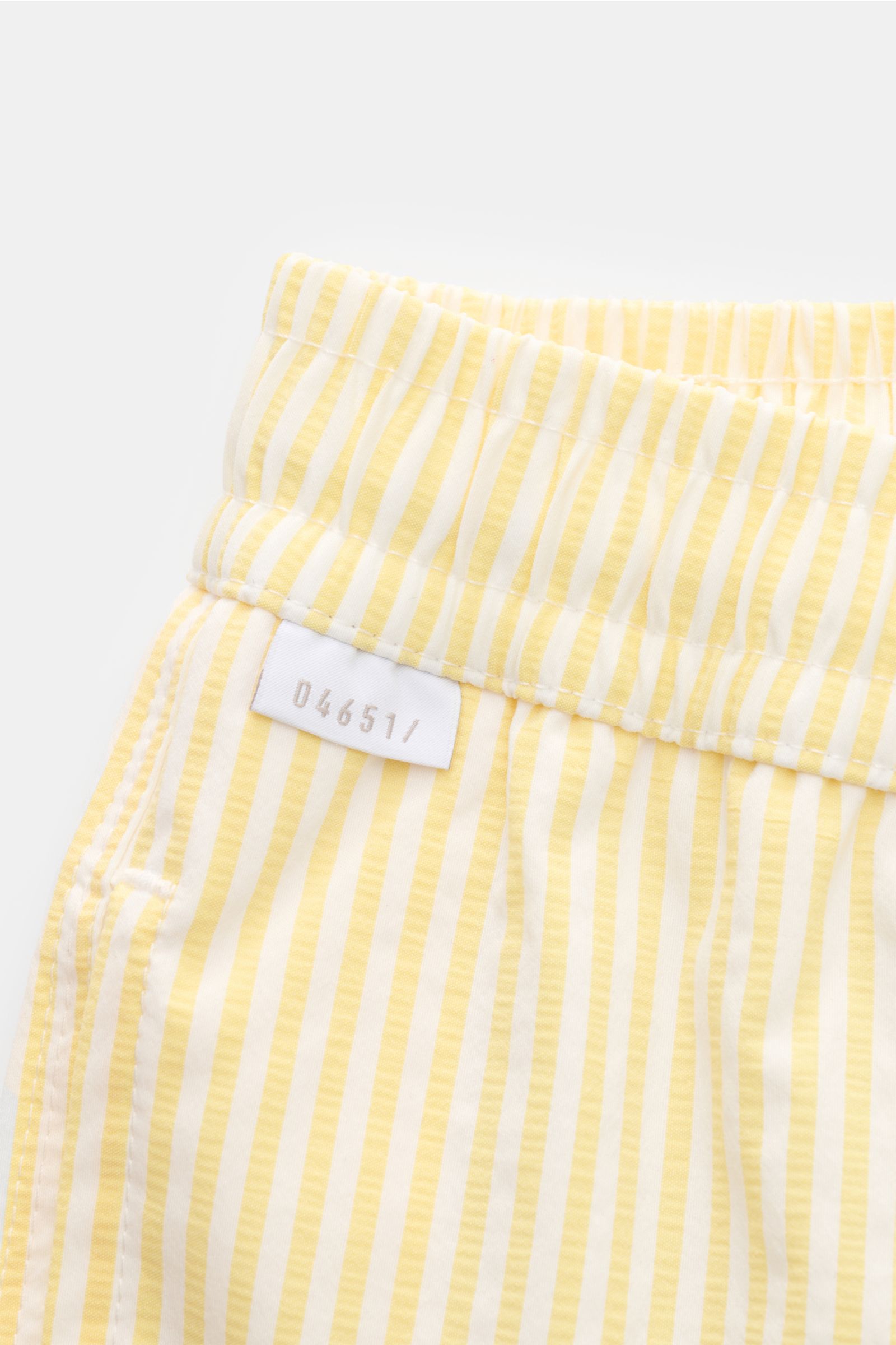 Close-up front side view of 04651/ A trip in a bag Swim shorts pastel yellow/white striped with elastic waistband and label.

Description: Perfect for your next summer holiday: With their modern striped pattern, these swim shorts by 04651/ A TRIP IN A 