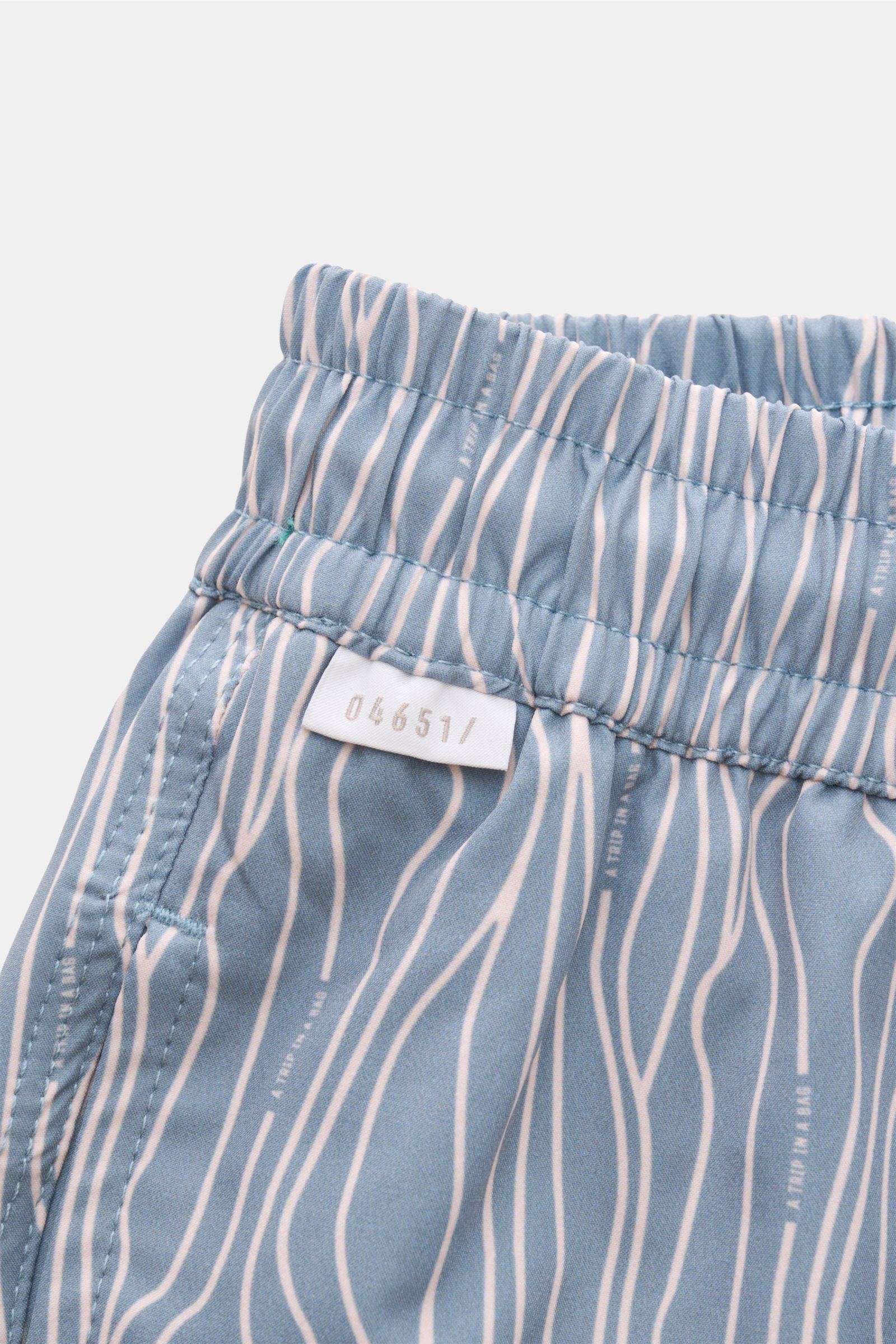 Close-up side view of the elasticated waistband and side pocket of 04651/ A trip in a bag Swim shorts 'Superkilen' smoky blue/white patterned with an all-over Copenhagen Superkilen park print. An eye-catching piece for summer: With their all-over print in